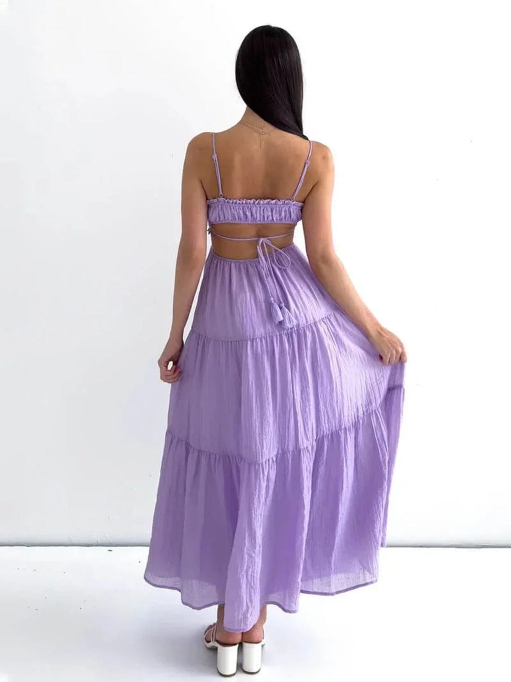 Woman in tiered midi dress with cut-outs and tassels.