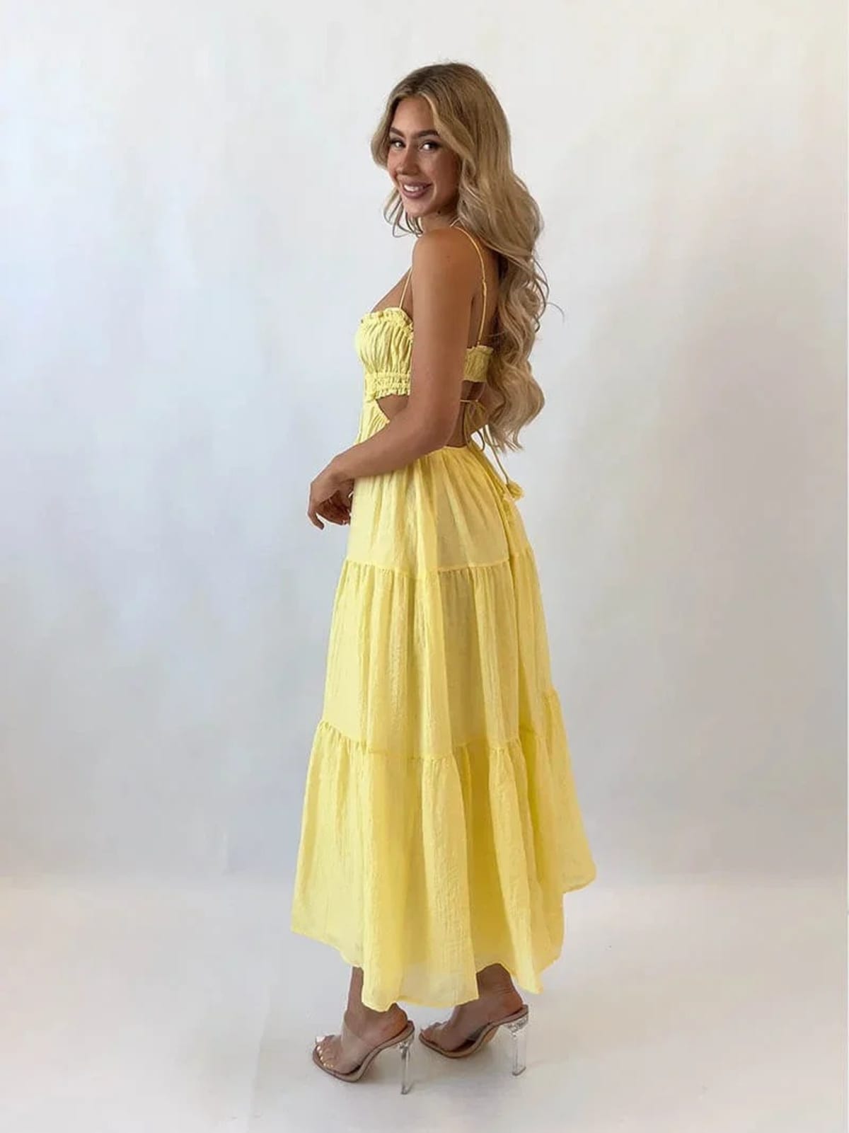 Woman in tiered midi dress with cut-outs and tassels.