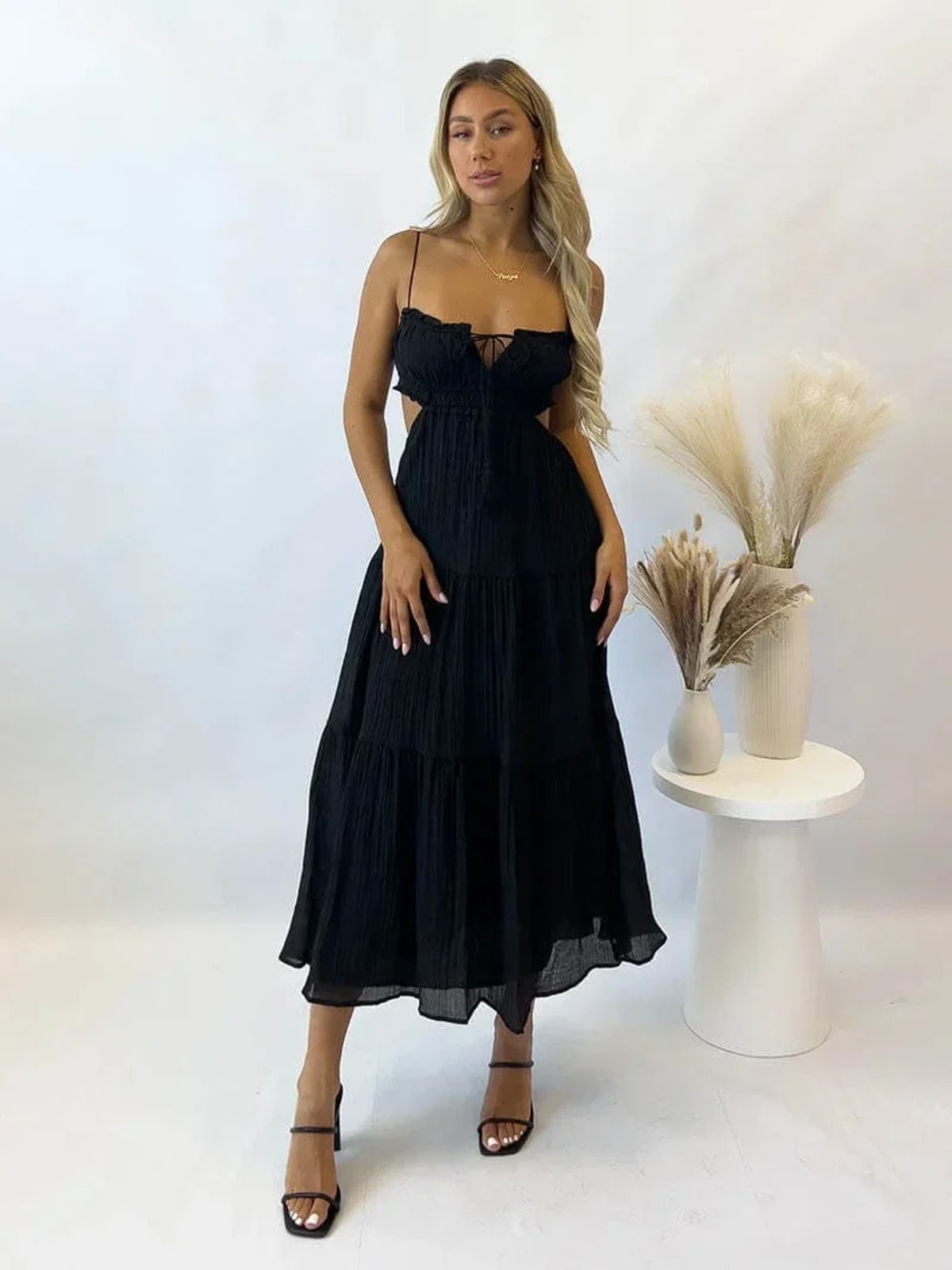 Woman in tiered midi dress with cut-outs and tassels.