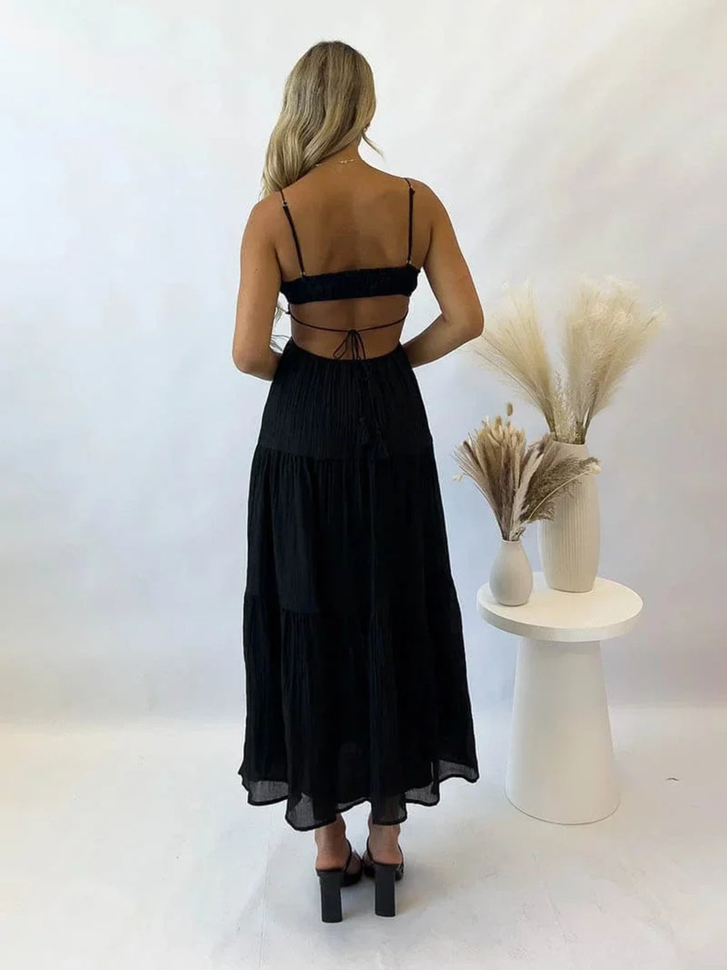 Woman in tiered midi dress with cut-outs and tassels.