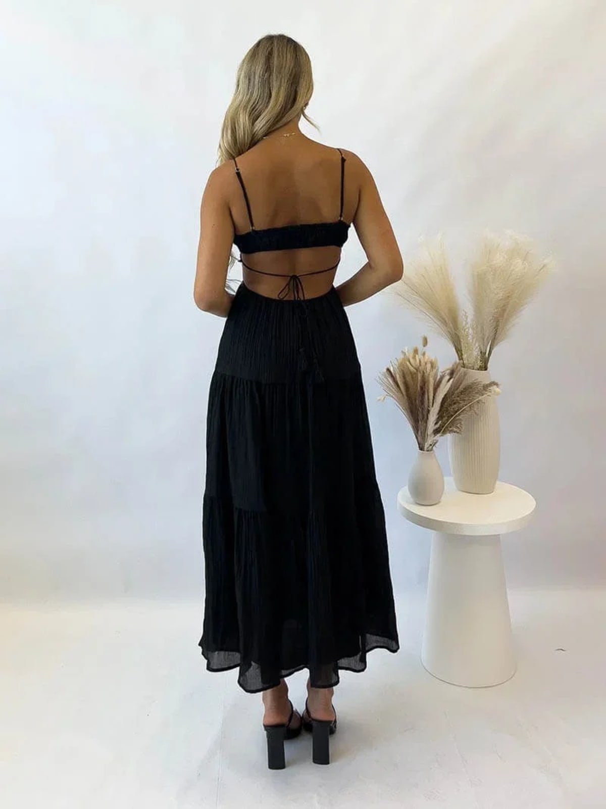Woman in tiered midi dress with cut-outs and tassels.