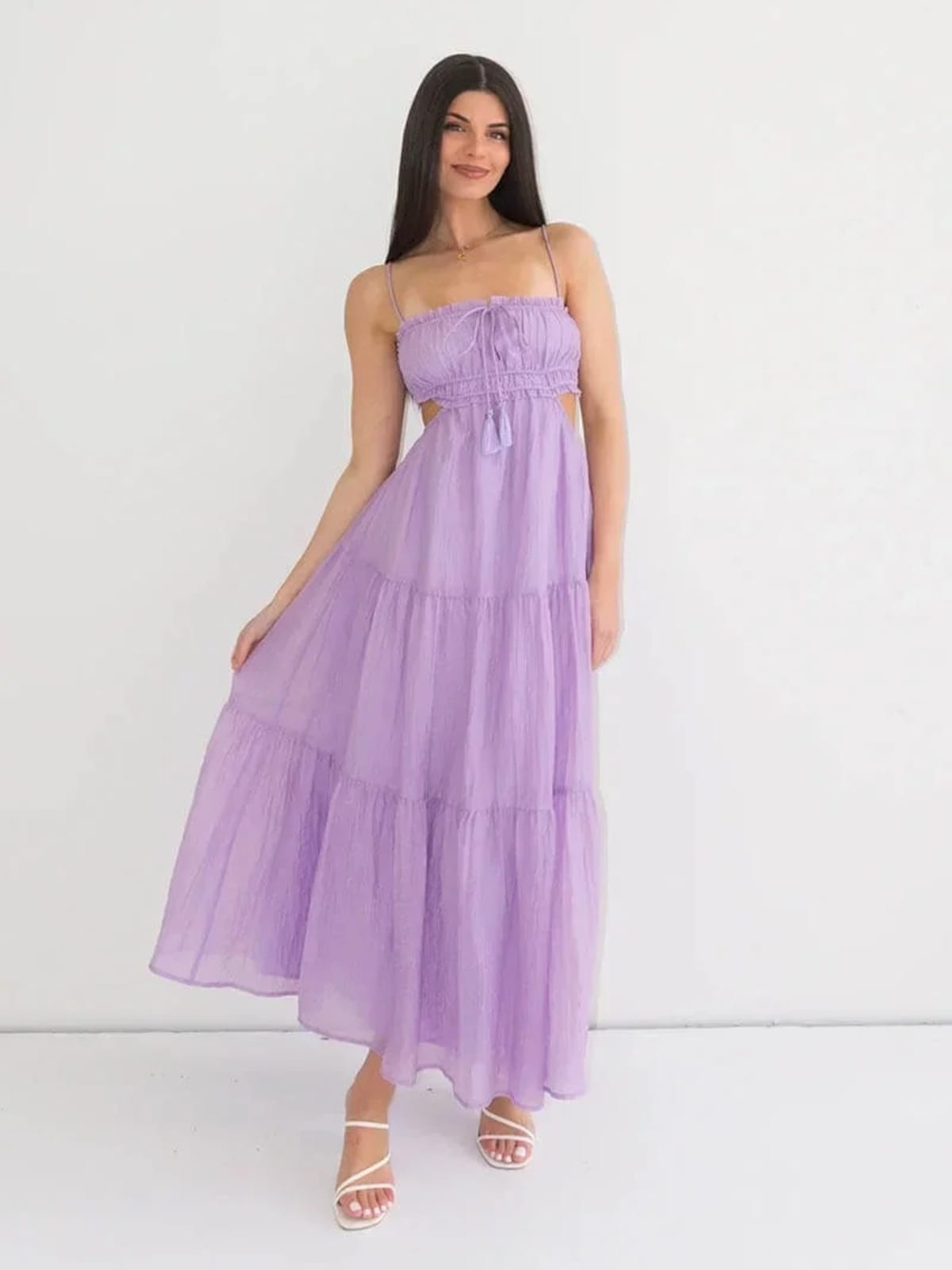 Woman in tiered midi dress with cut-outs and tassels.