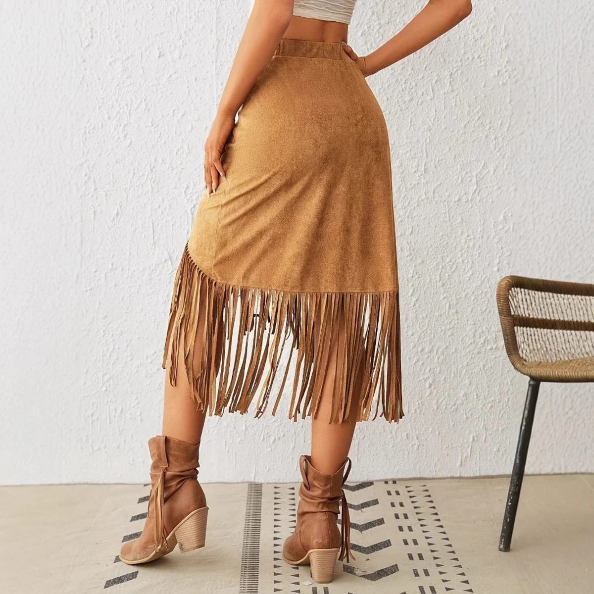 Woman wearing a midi skirt with fringe trim and asymmetrical hem.