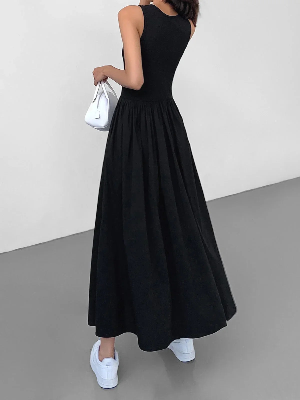 Person wearing a sleeveless maxi dress with a gathered skirt.