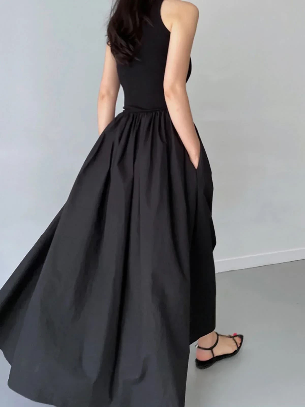 Person wearing a sleeveless maxi dress with a gathered skirt.