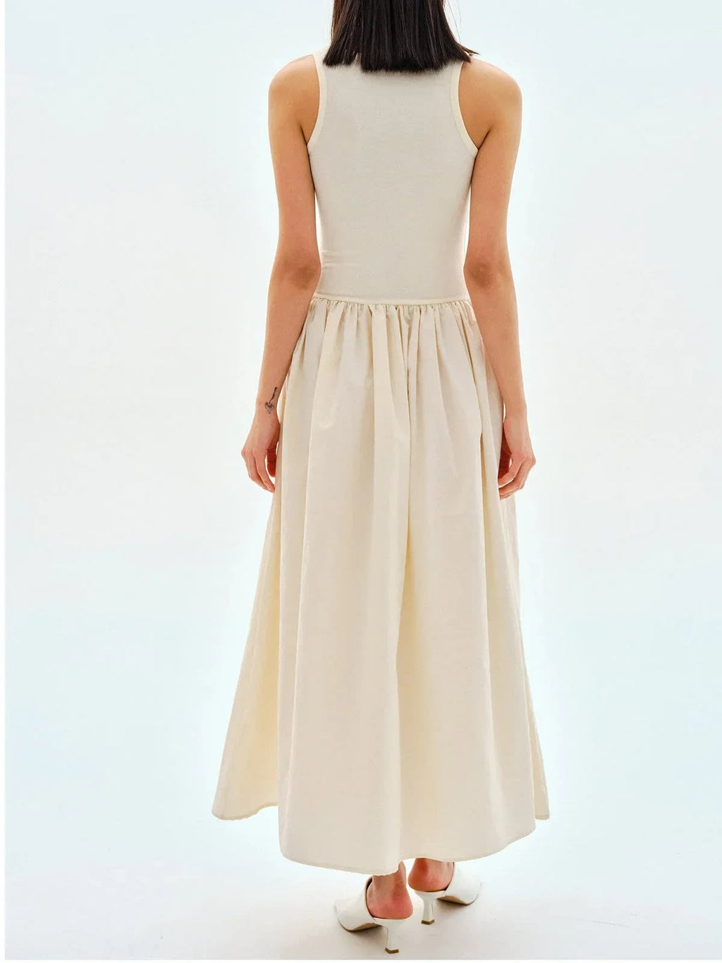Person wearing a sleeveless maxi dress with a gathered skirt.