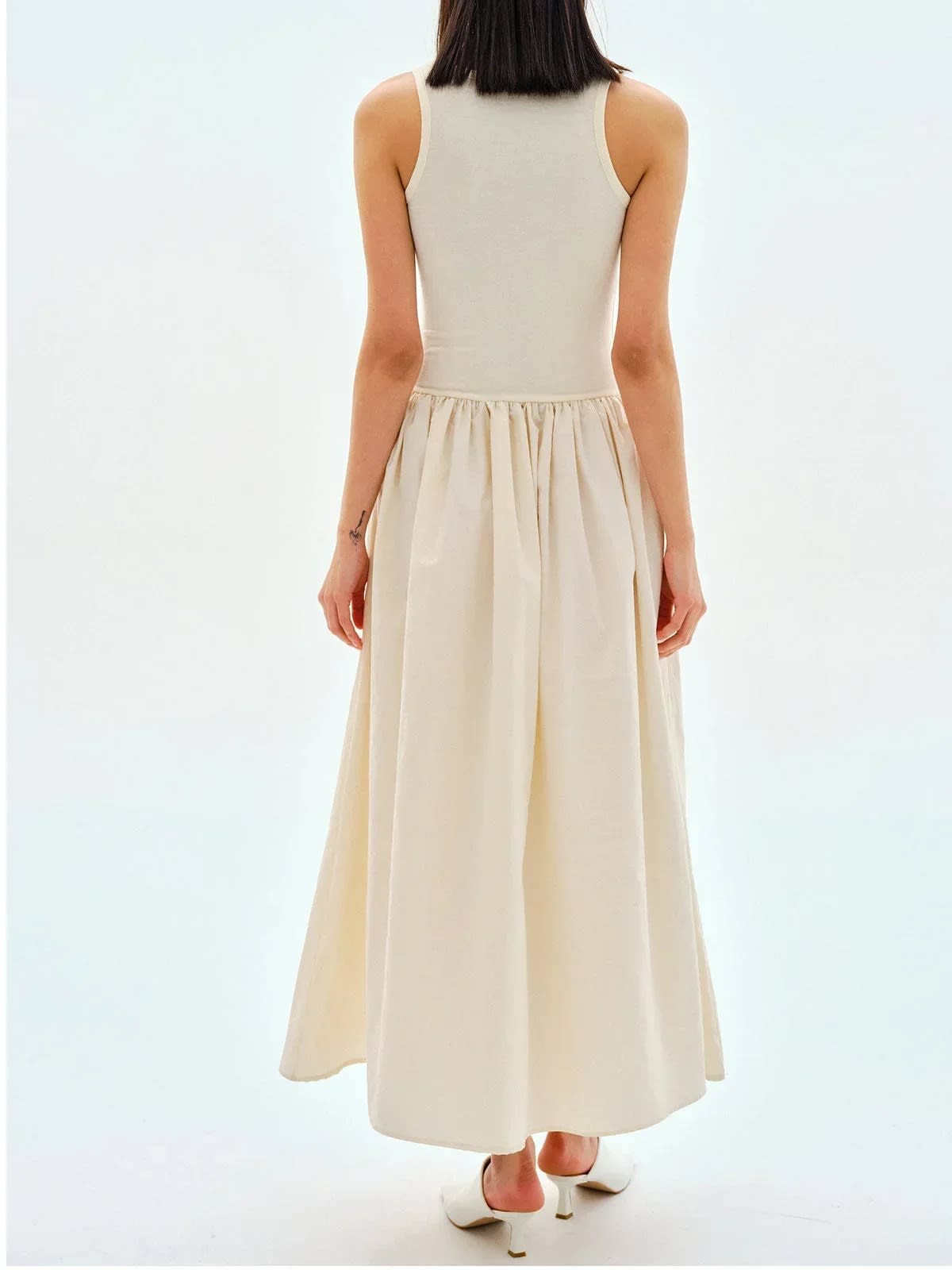 Person wearing a sleeveless maxi dress with a gathered skirt.
