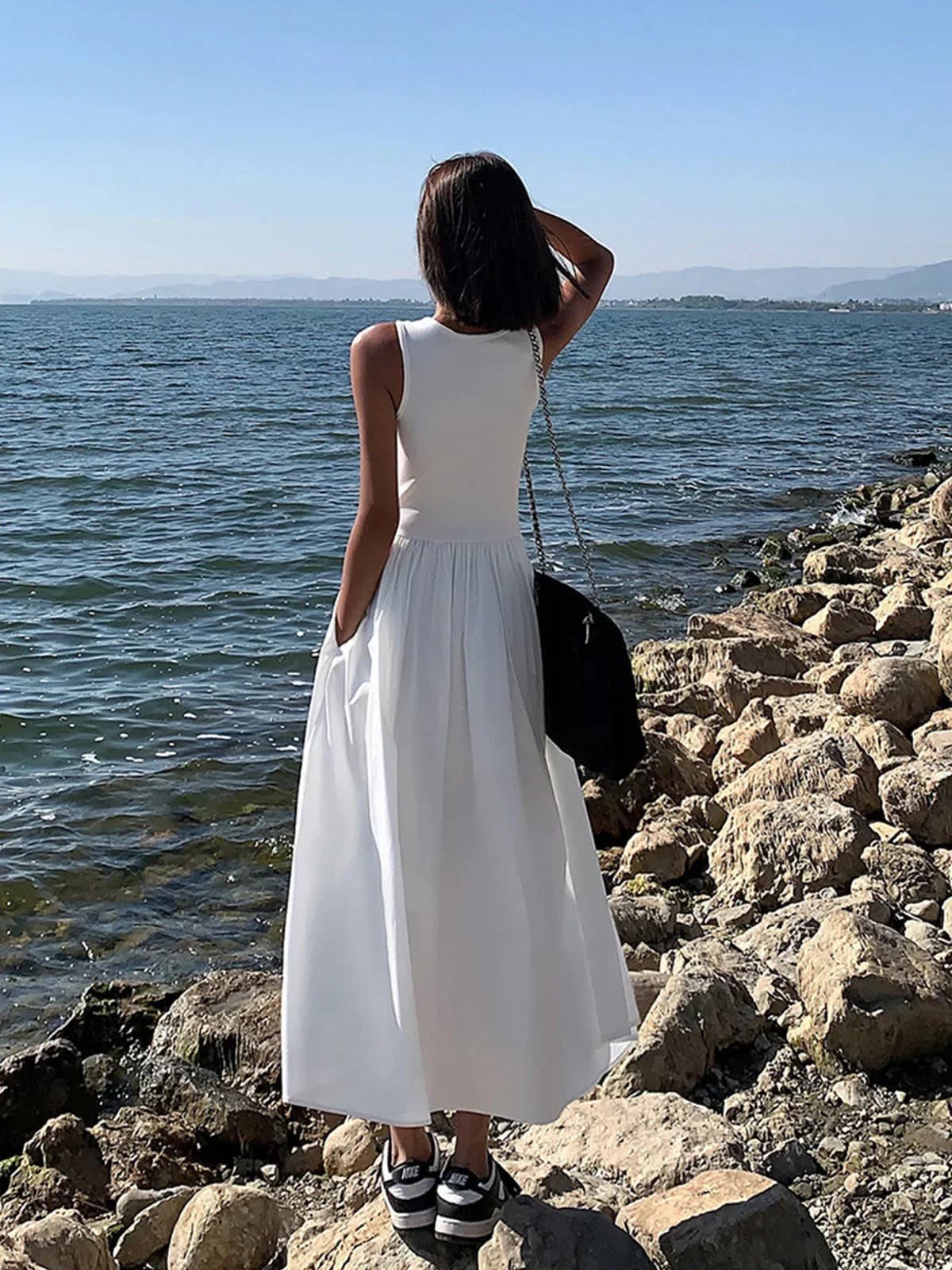 Person wearing a sleeveless maxi dress with a gathered skirt.