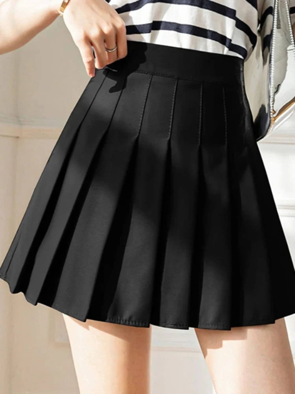 Person wearing a pleated mini skirt with a striped top.