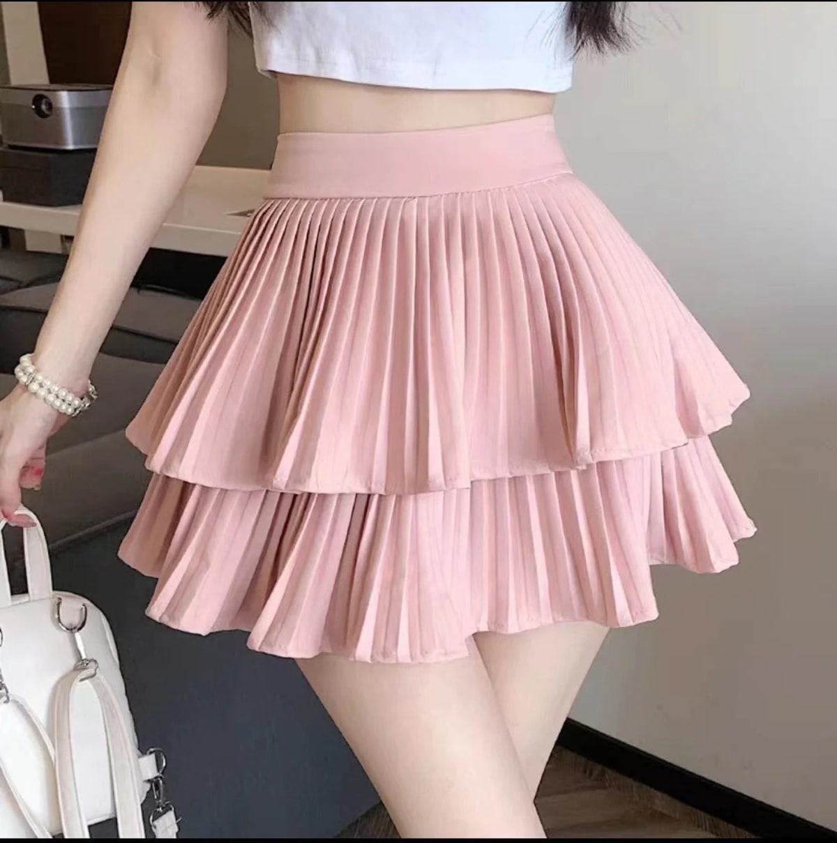 Light pink pleated tiered mini skirt with ruffle hem and wide waistband.