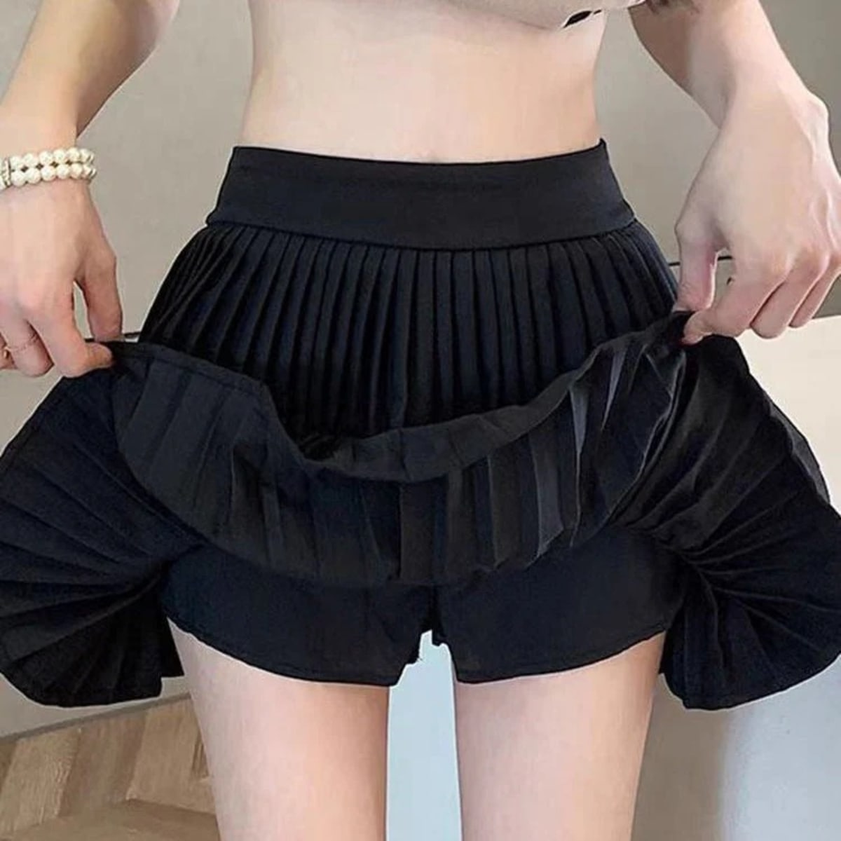 Light pink pleated tiered mini skirt with ruffle hem and wide waistband.