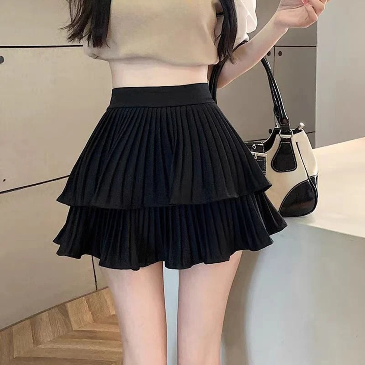 Light pink pleated tiered mini skirt with ruffle hem and wide waistband.