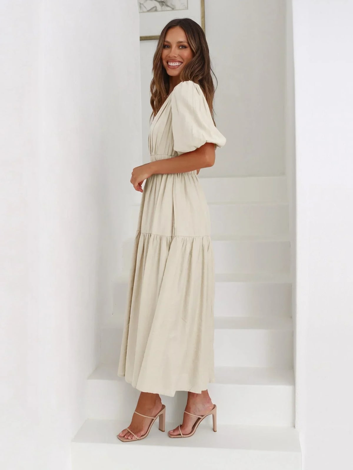Woman in V-neck maxi dress with puff sleeves and smocked waist.