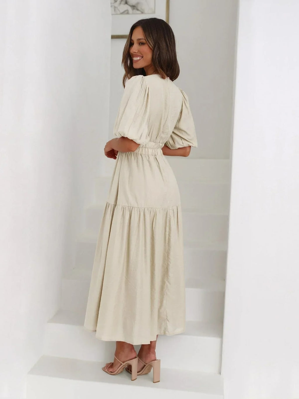 Woman in V-neck maxi dress with puff sleeves and smocked waist.