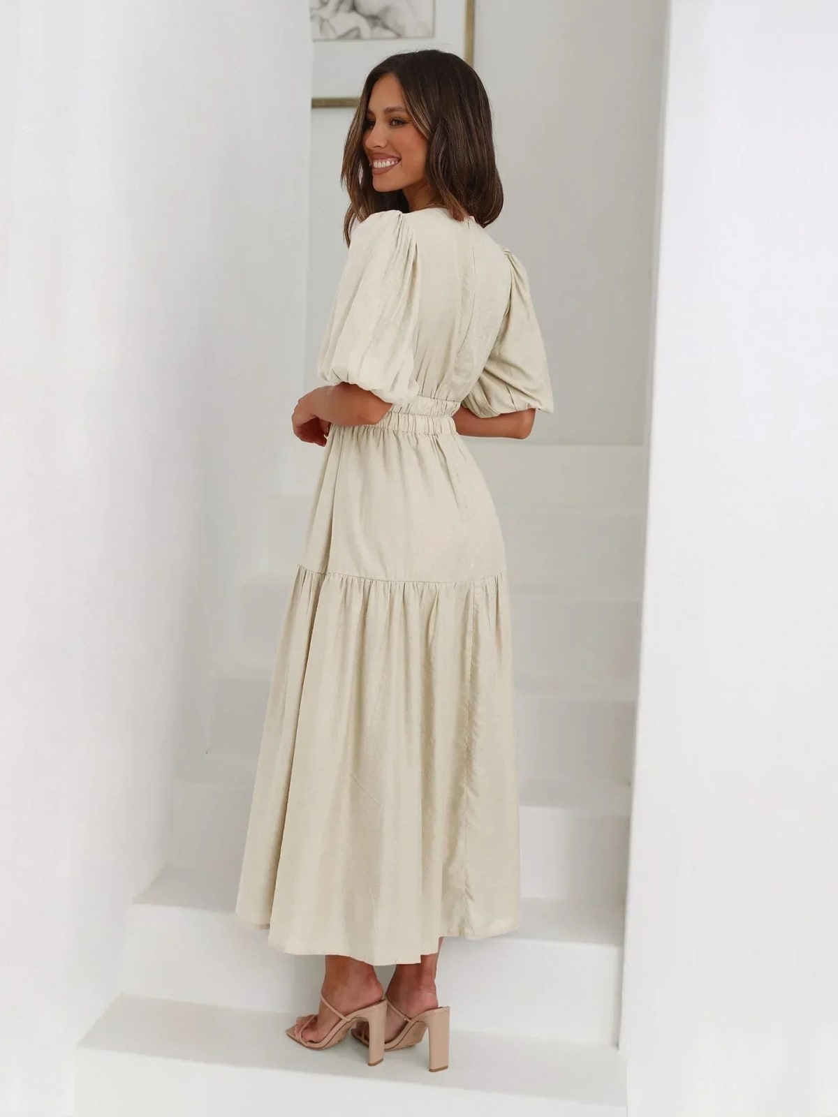 Woman in V-neck maxi dress with puff sleeves and smocked waist.