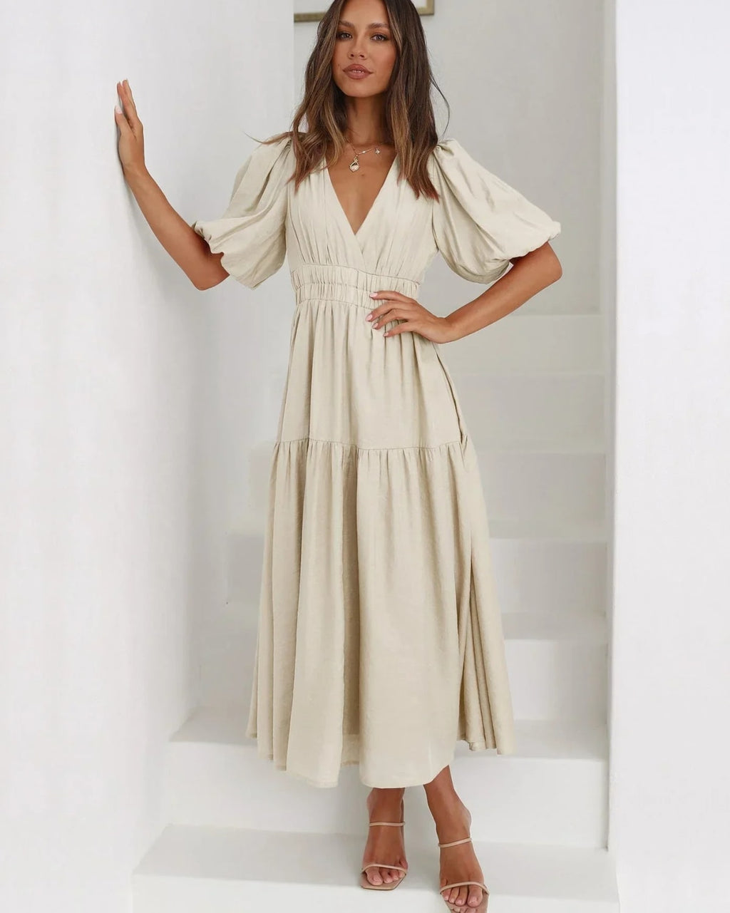 Woman in V-neck maxi dress with puff sleeves and smocked waist.