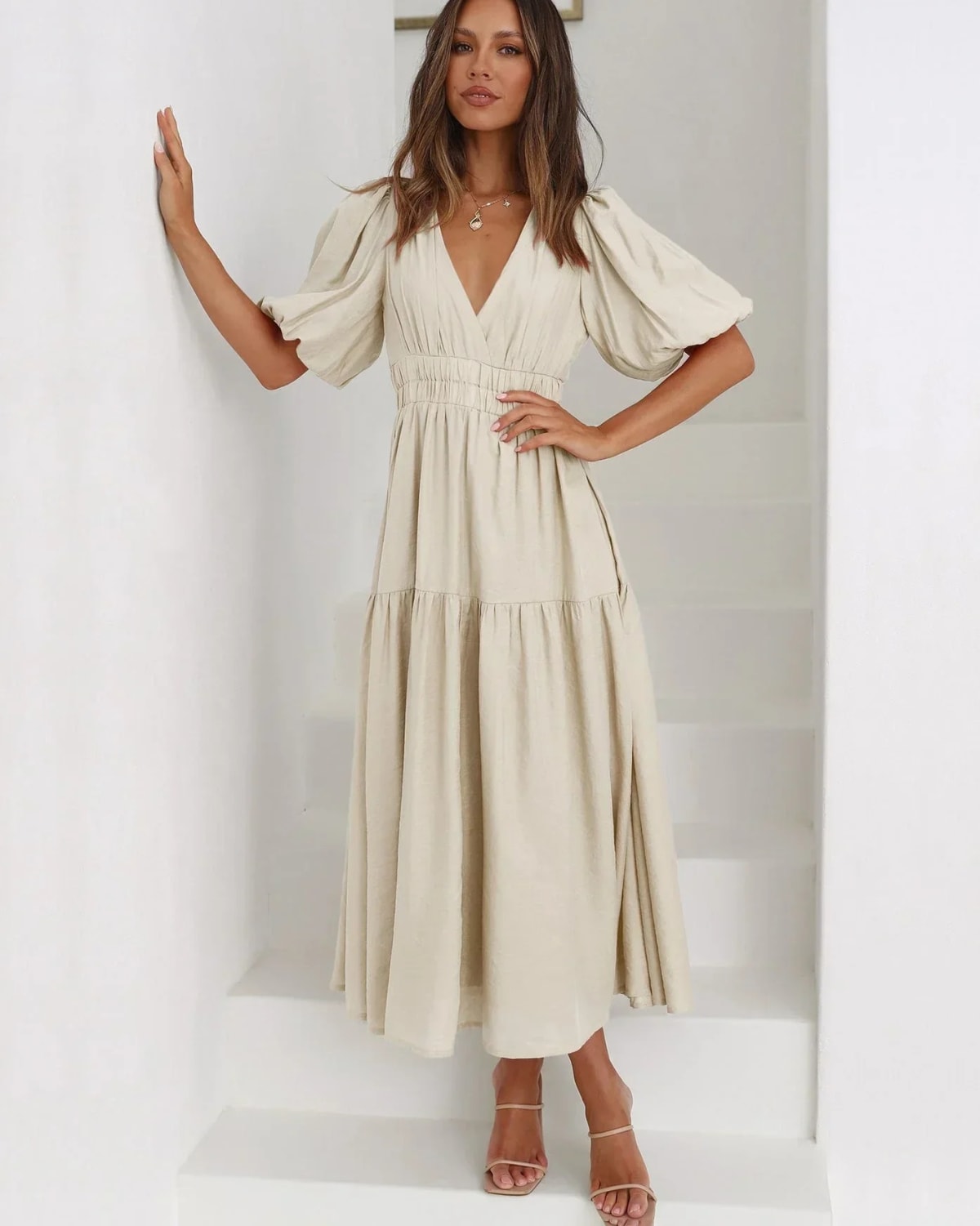 Woman in V-neck maxi dress with puff sleeves and smocked waist.