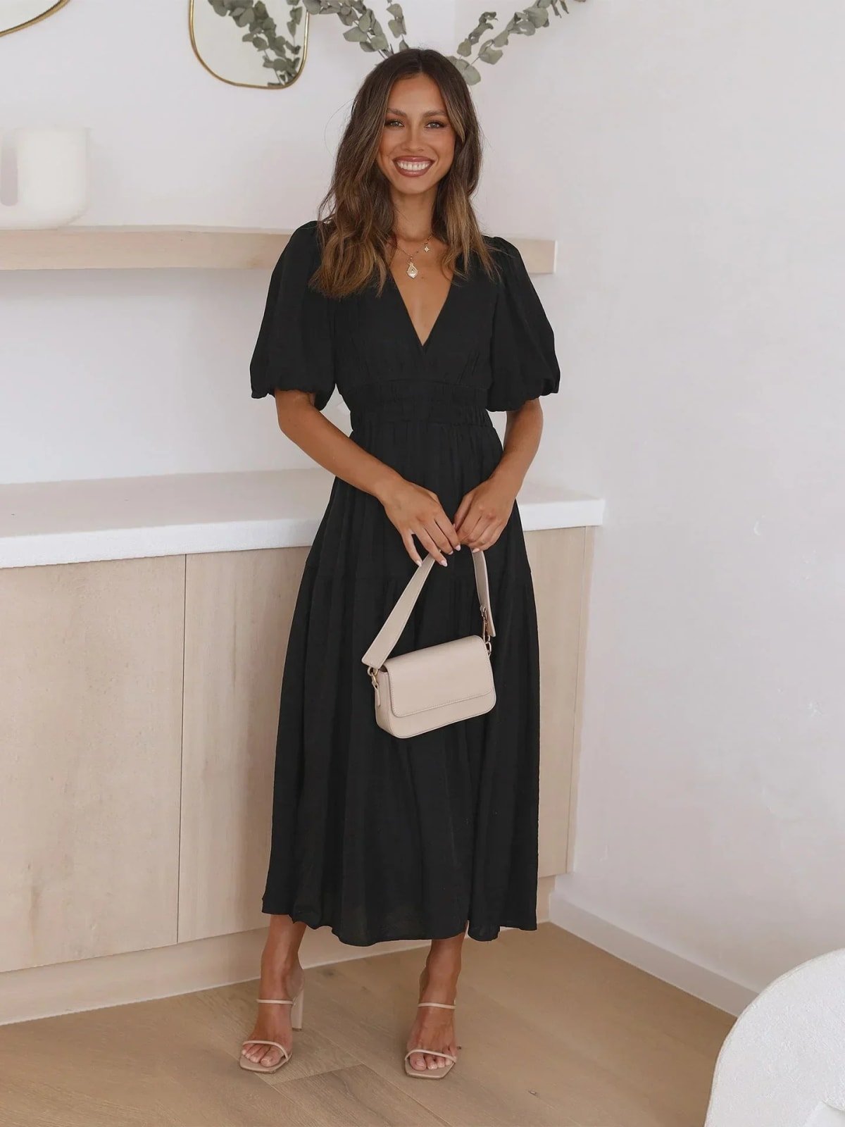 Woman in V-neck maxi dress with puff sleeves and smocked waist.