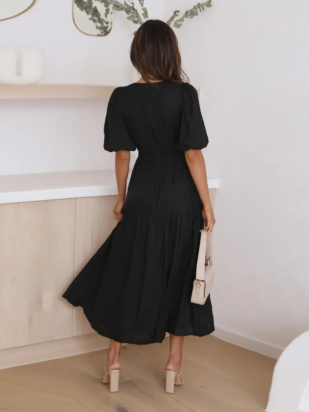Woman in V-neck maxi dress with puff sleeves and smocked waist.