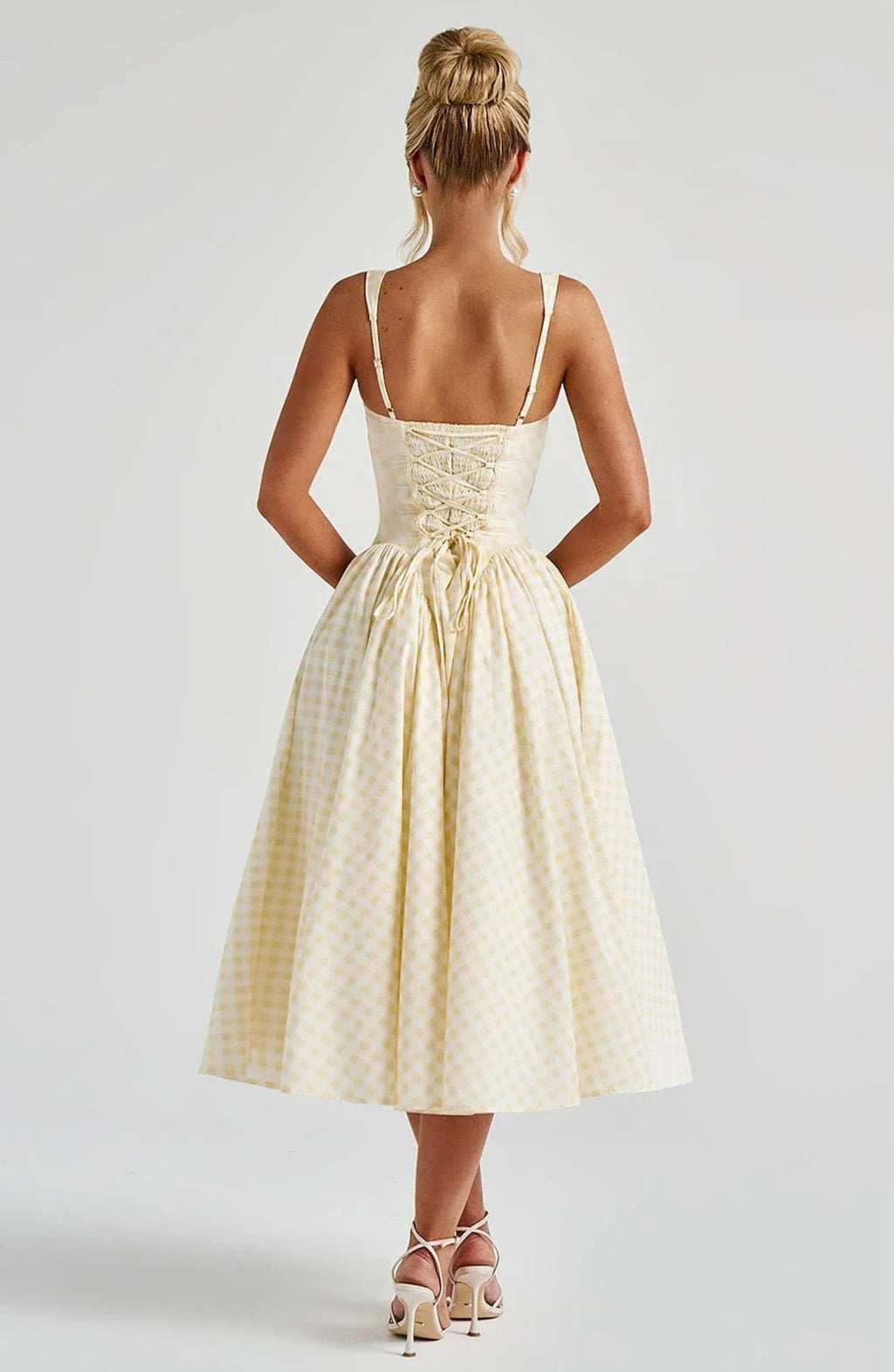 Woman wearing a gingham midi dress with a structured bodice.