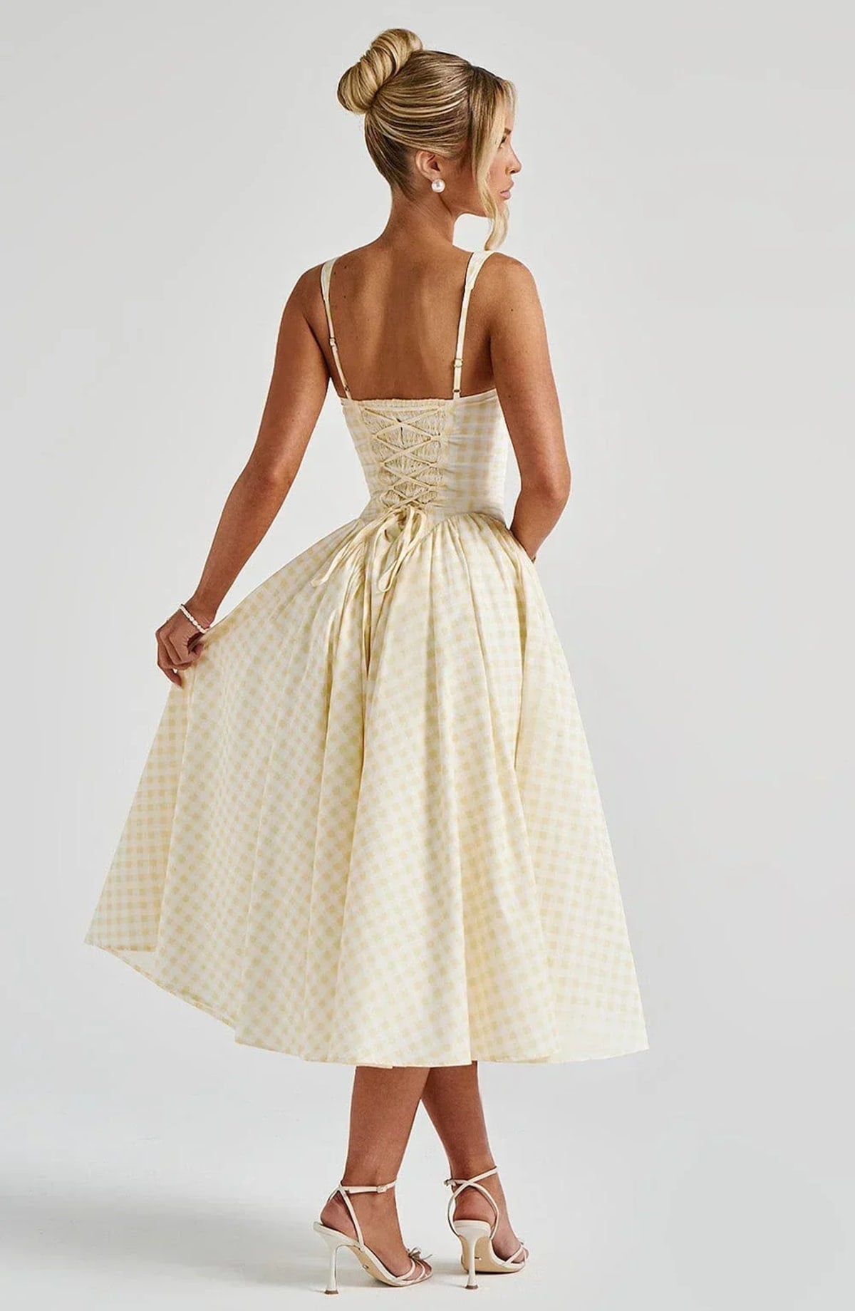 Woman wearing a gingham midi dress with a structured bodice.
