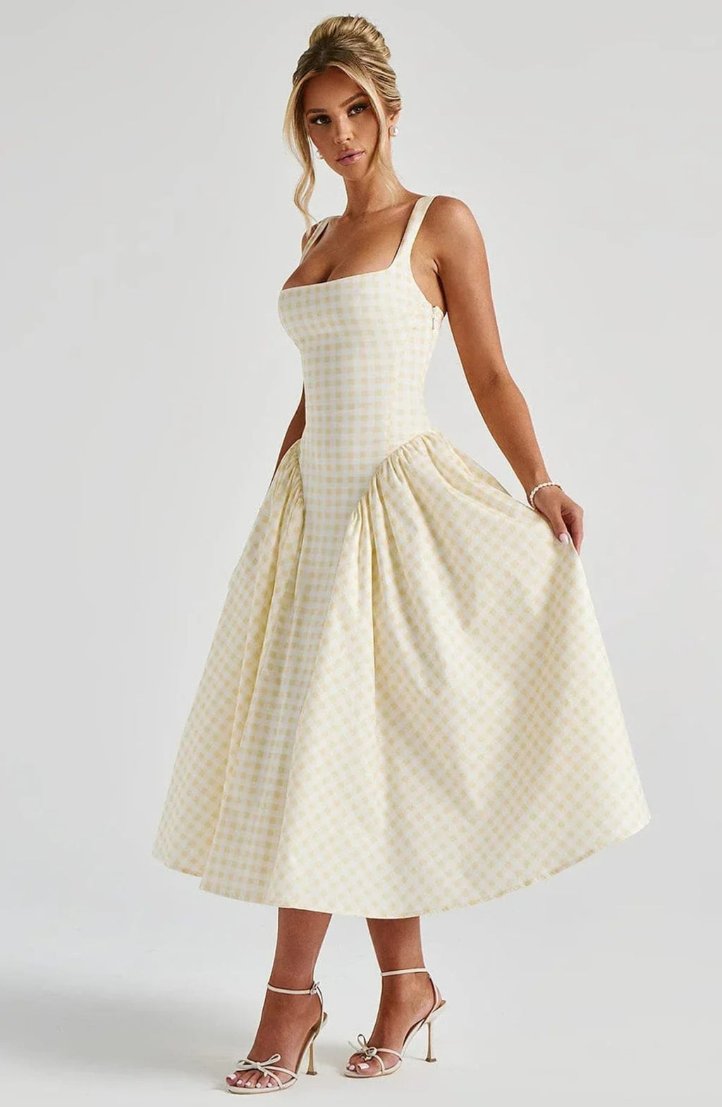 Woman wearing a gingham midi dress with a structured bodice.