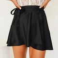 Model wearing a black satin wrap mini skirt with tie waist.