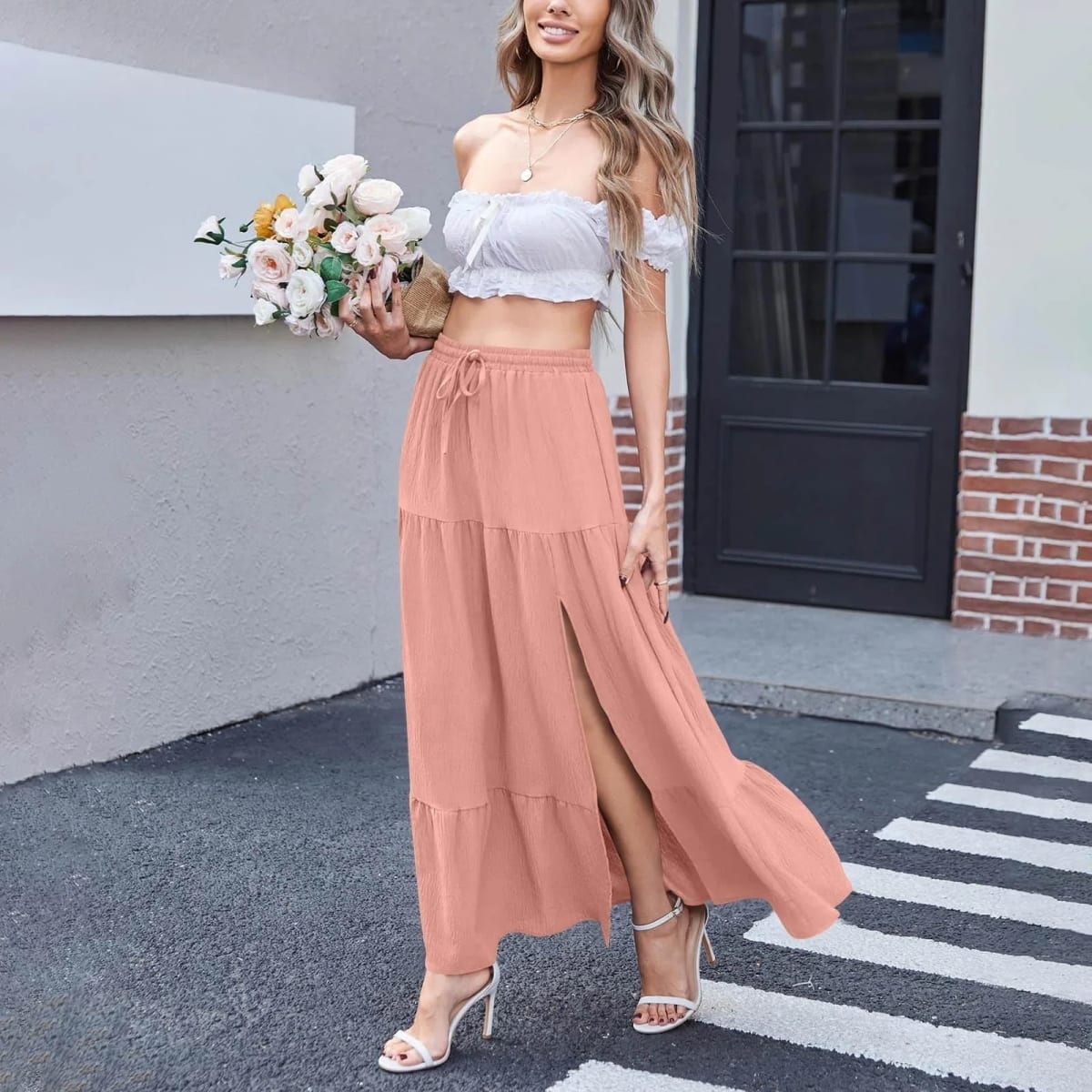 Woman wearing a tiered maxi skirt with a side slit and crop top.