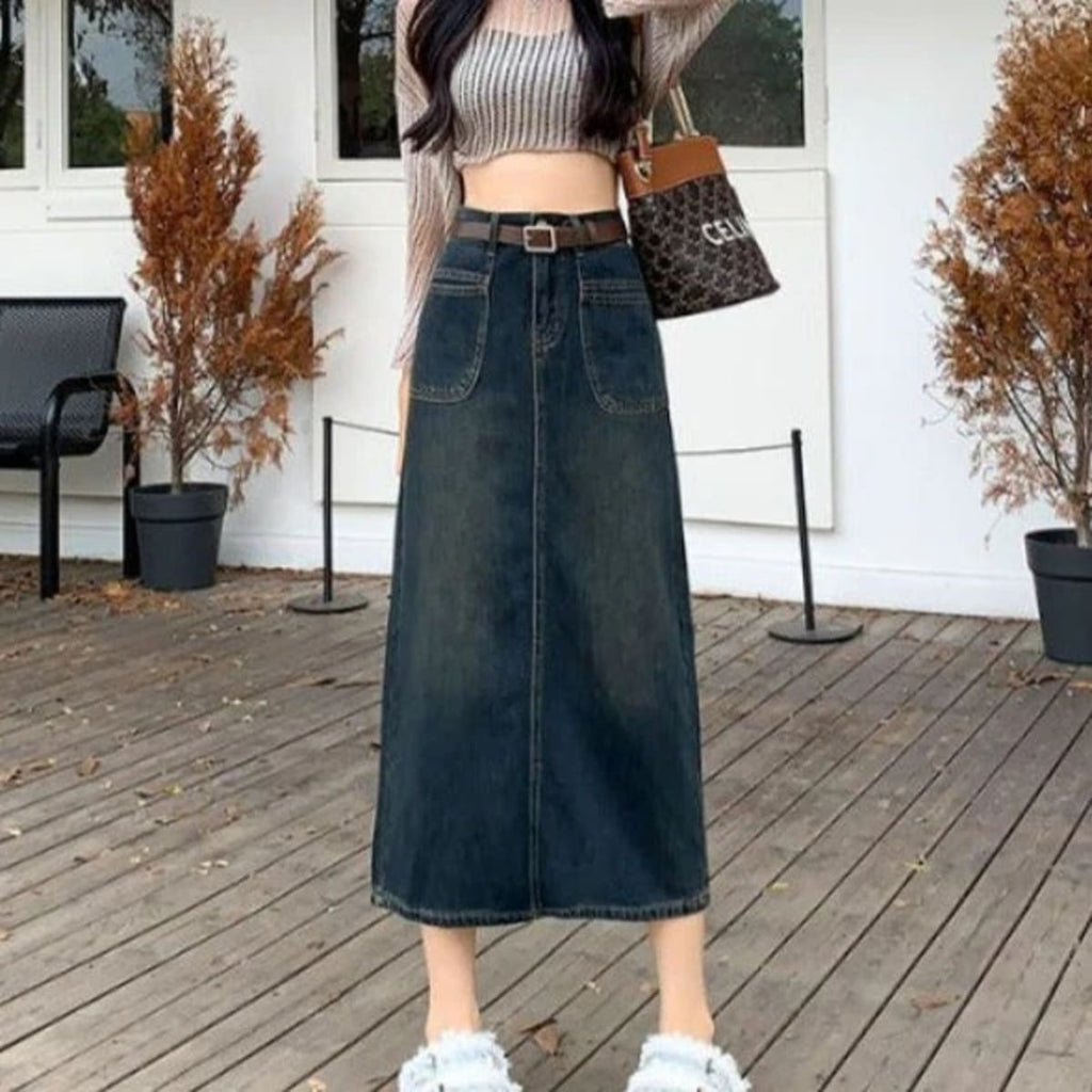 Woman wearing A-line midi denim skirt with front pockets and belt.
