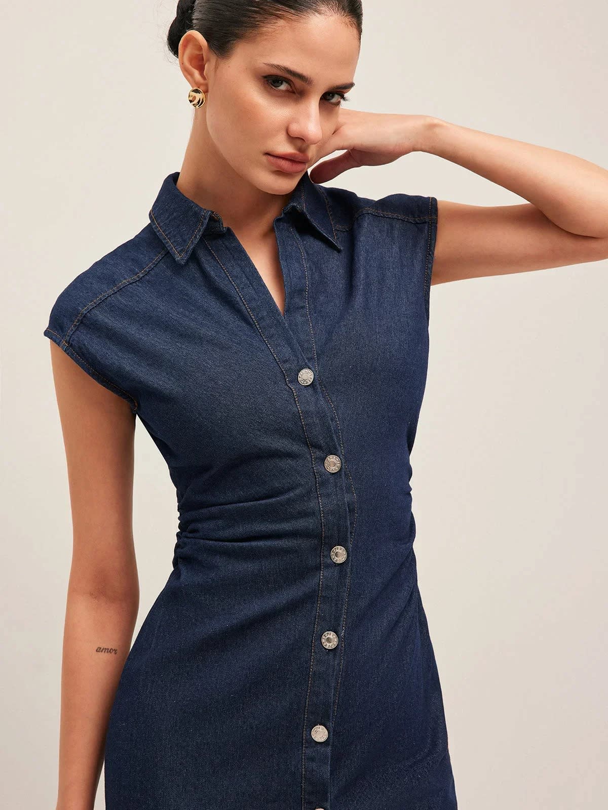 Woman wearing denim midi dress with cap sleeves and button-front.