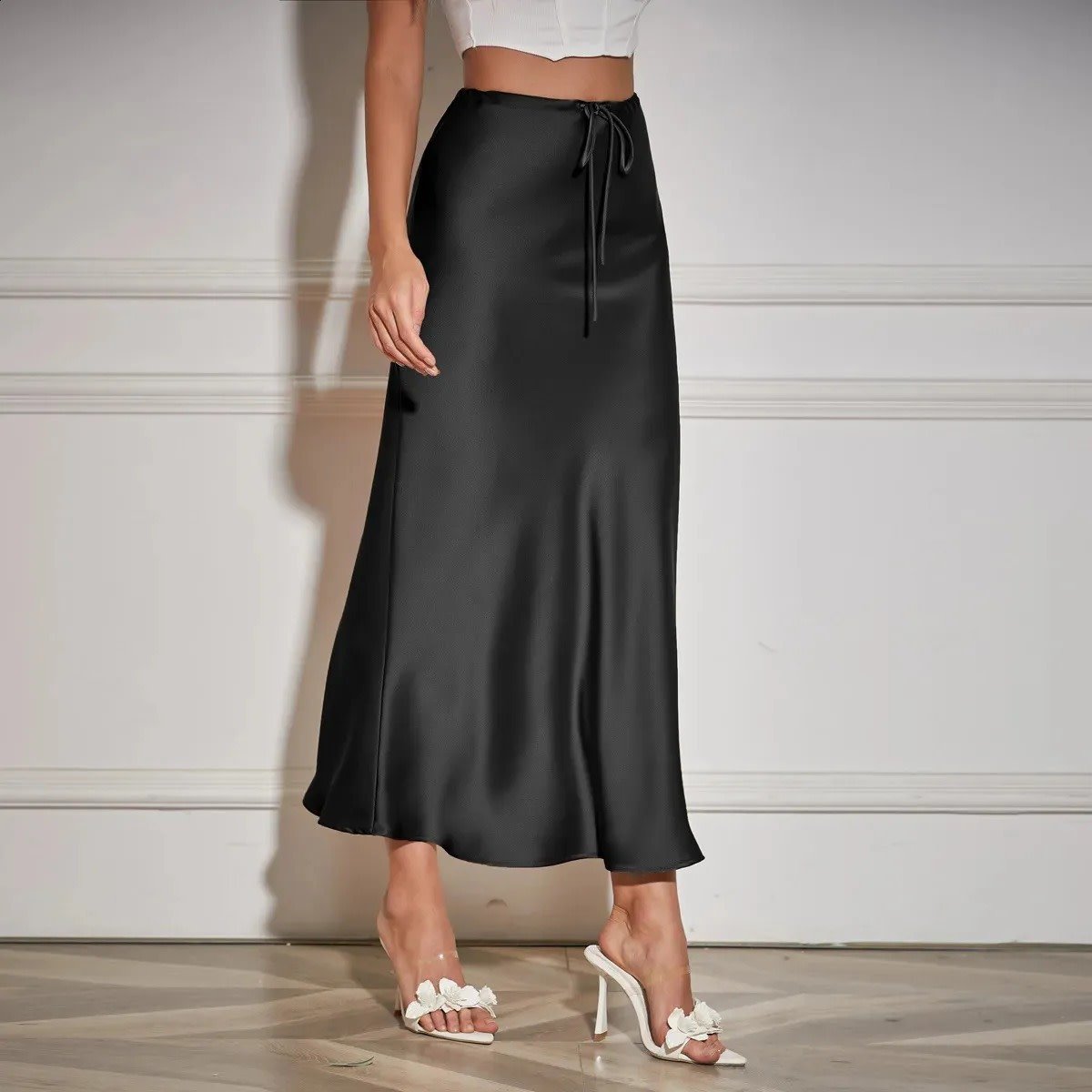 Woman wearing a satin maxi skirt with drawstring waist.