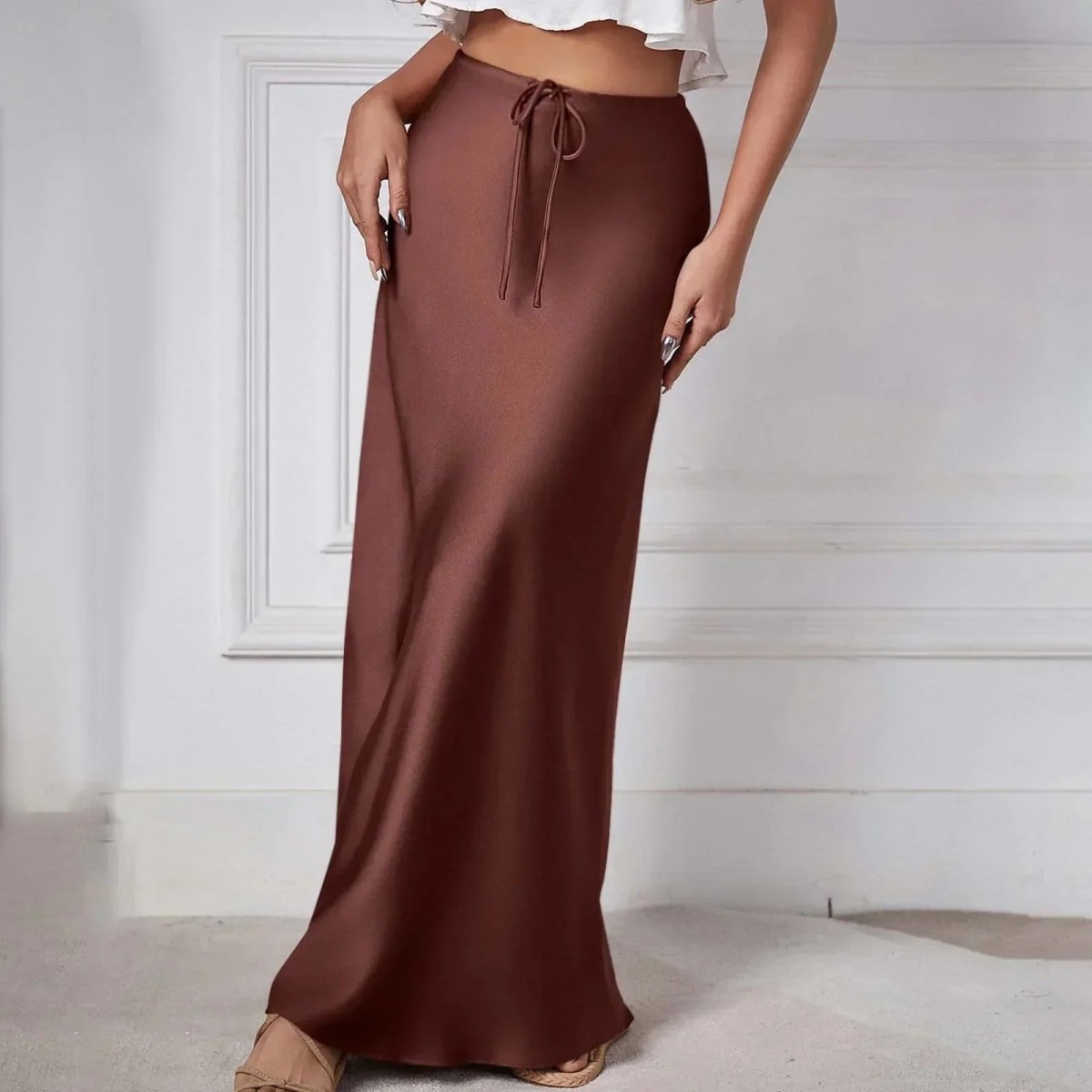 Woman wearing a satin maxi skirt with drawstring waist.