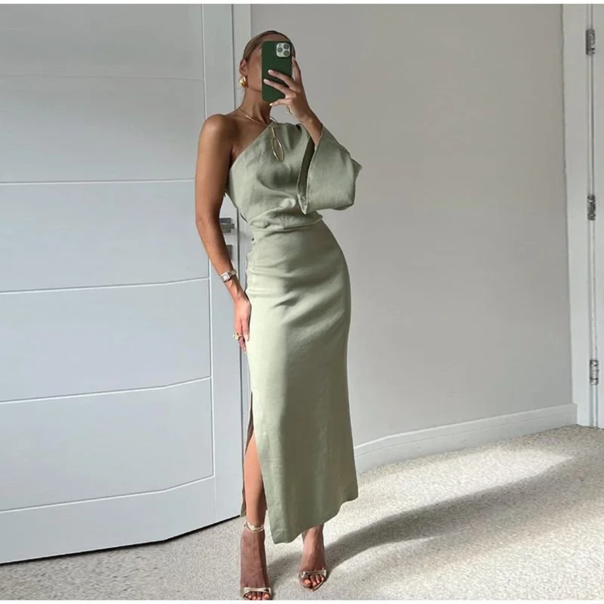 Woman in one-shoulder sage green top and midi skirt set.