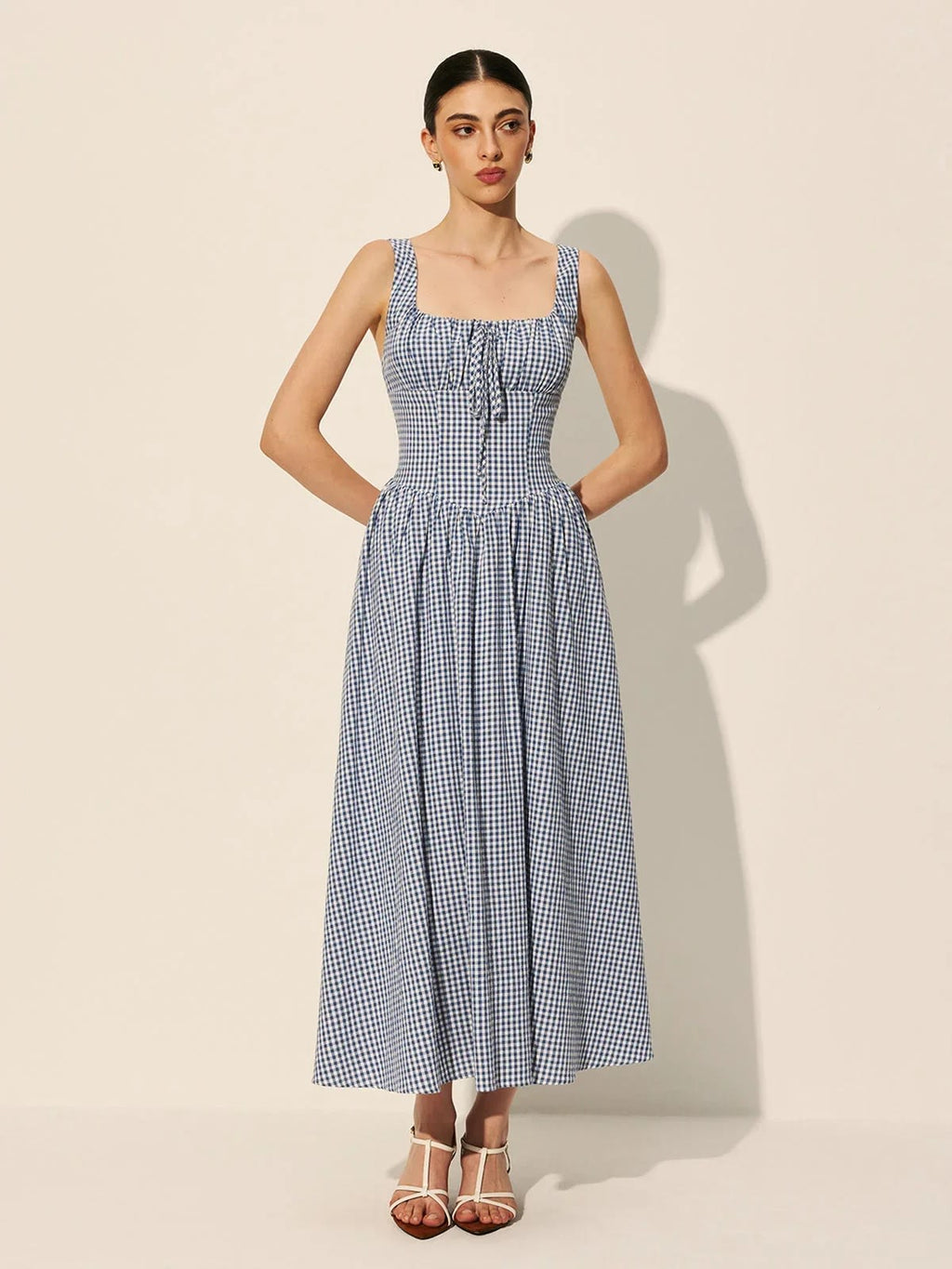 Woman wearing a gingham midi dress with square neck and smocked bodice.