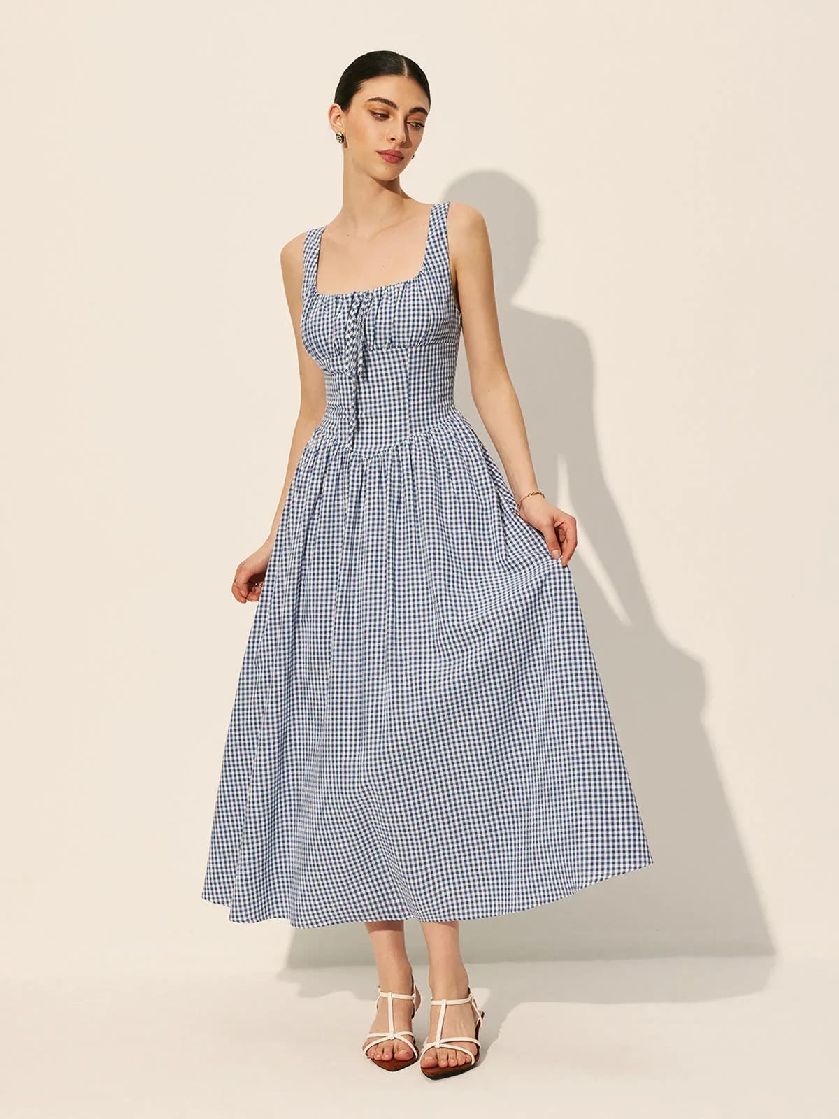 Woman wearing a gingham midi dress with square neck and smocked bodice.