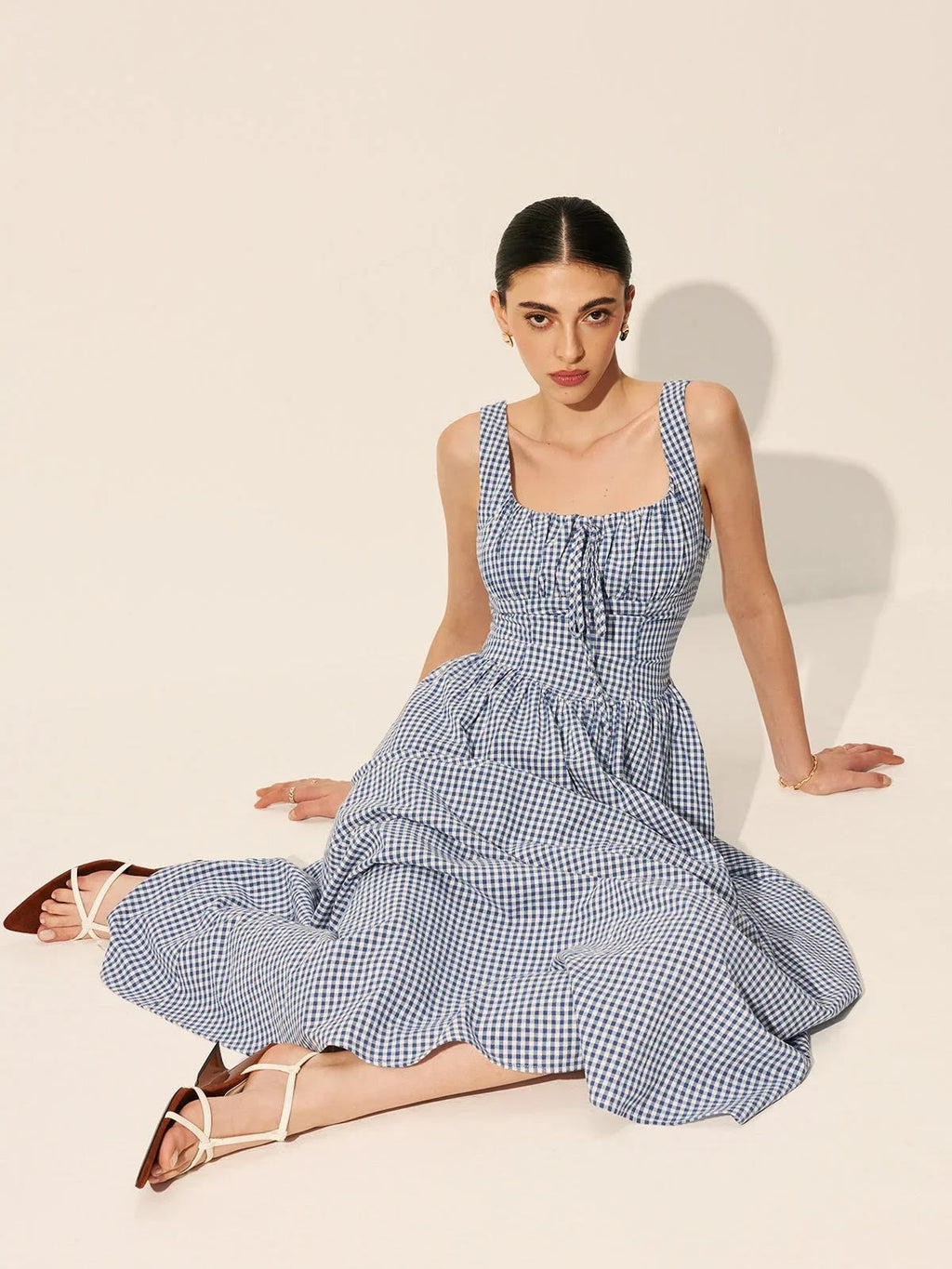 Woman wearing a gingham midi dress with square neck and smocked bodice.