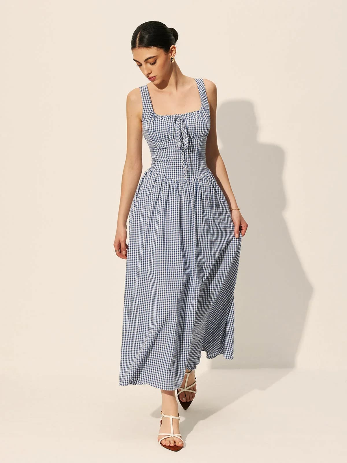 Woman wearing a gingham midi dress with square neck and smocked bodice.