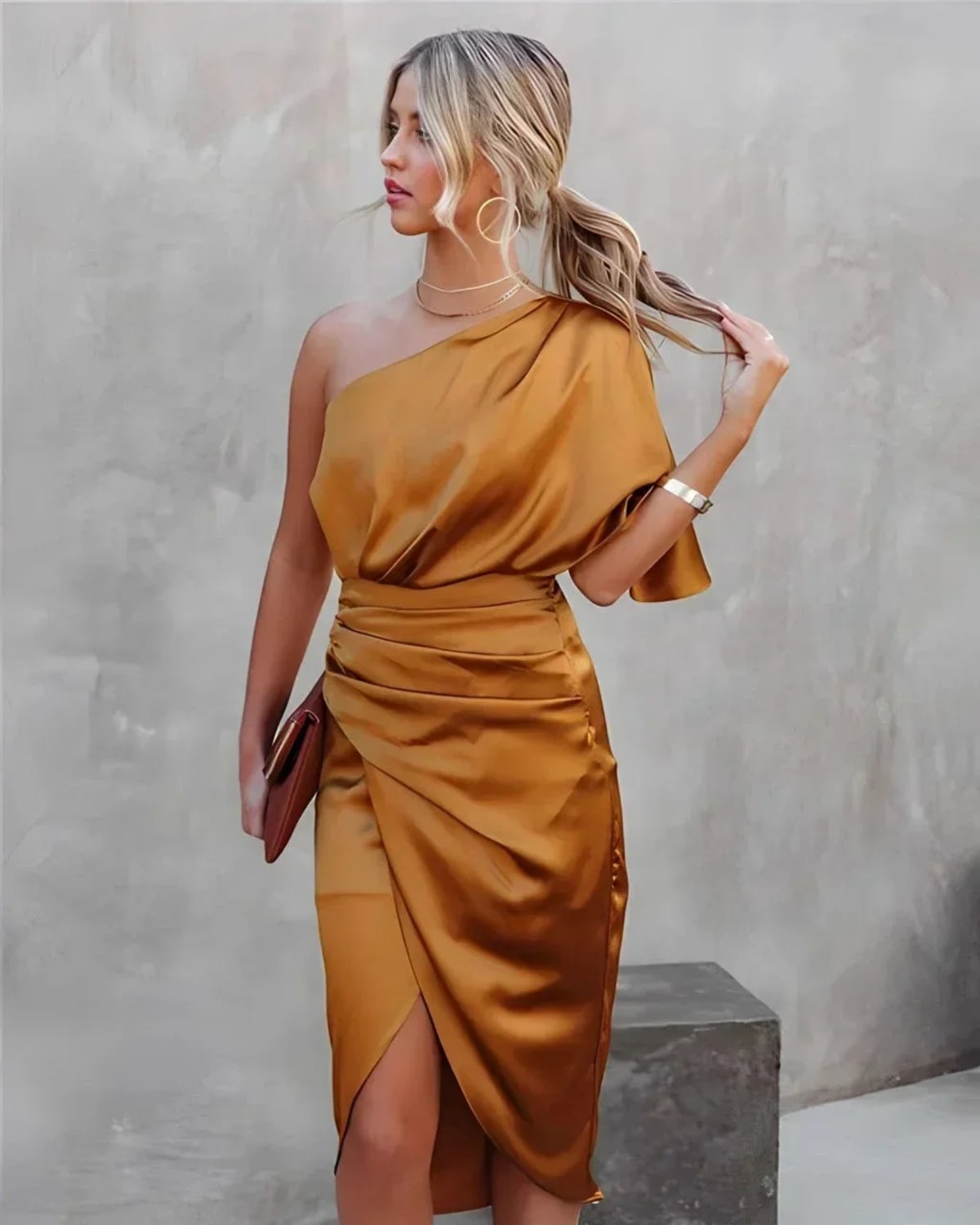 Woman in a one-shoulder black midi dress with draped bodice and ruched wrap skirt.