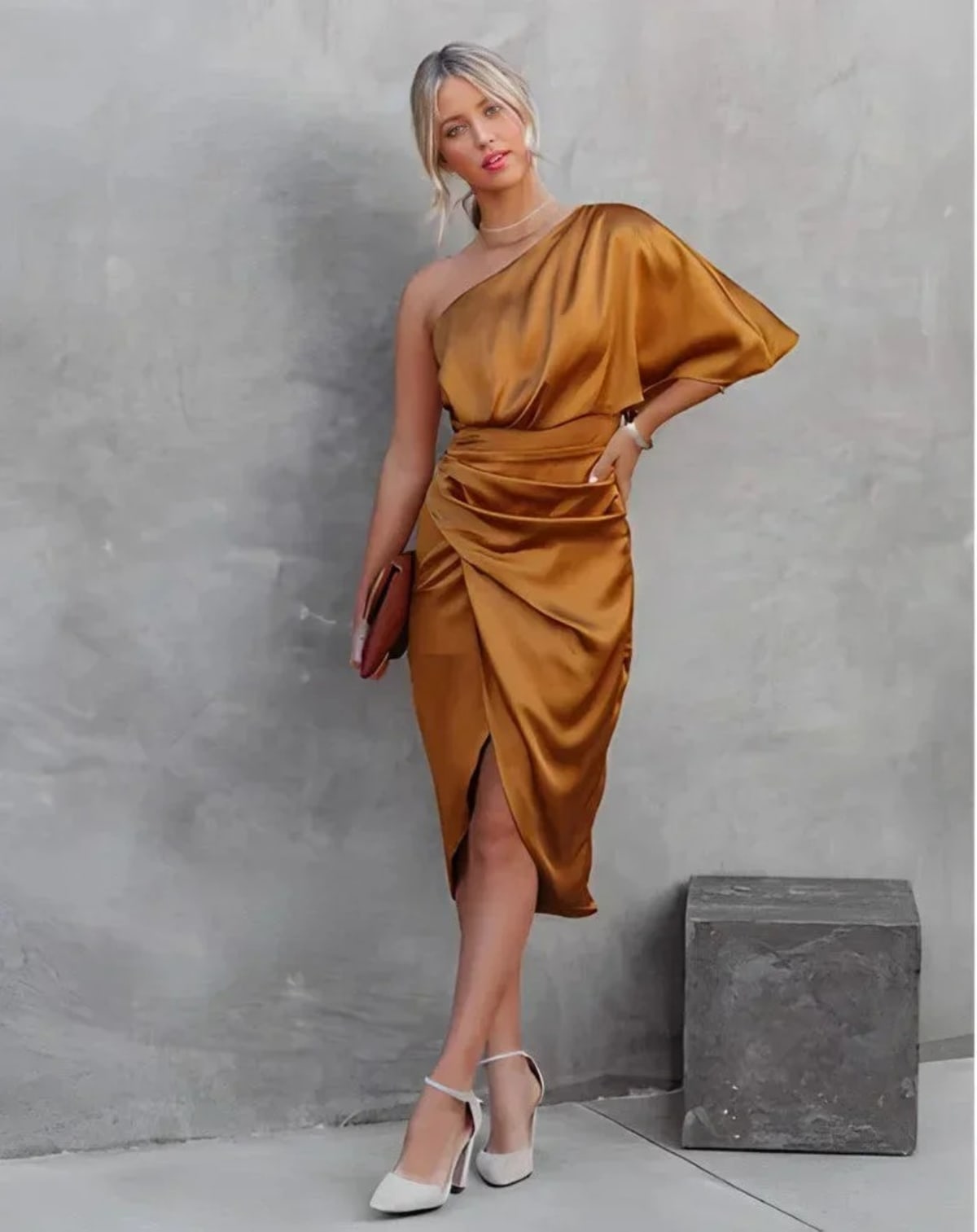 Woman in a one-shoulder black midi dress with draped bodice and ruched wrap skirt.