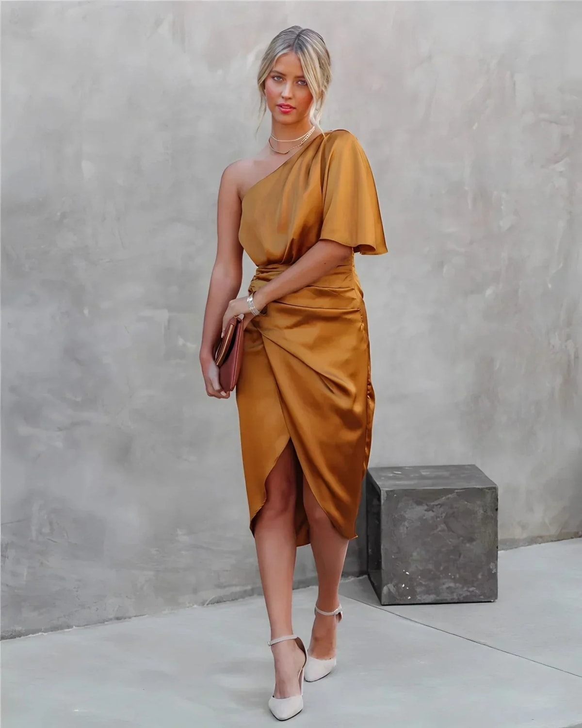 Woman in a one-shoulder black midi dress with draped bodice and ruched wrap skirt.