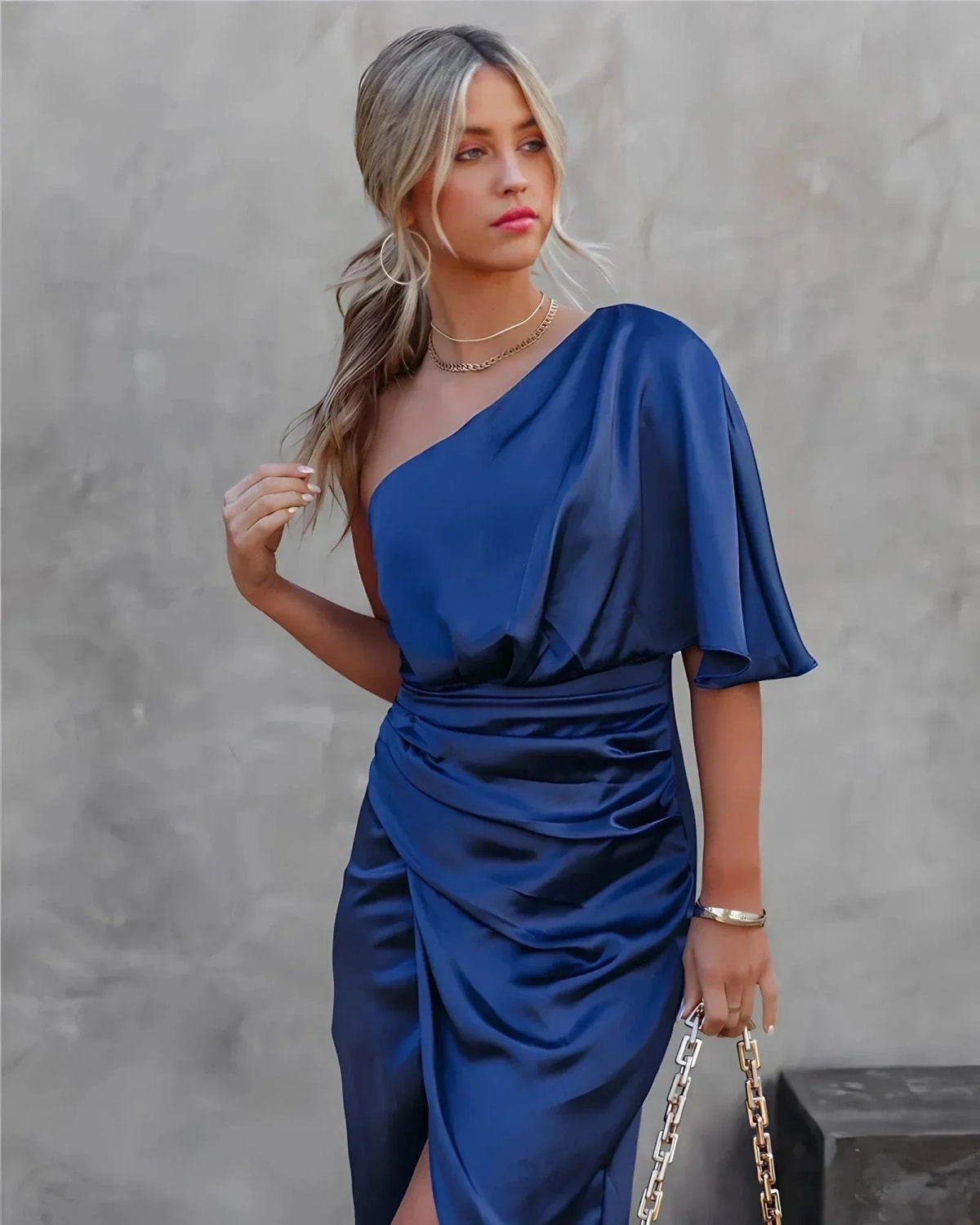 Woman in a one-shoulder black midi dress with draped bodice and ruched wrap skirt.