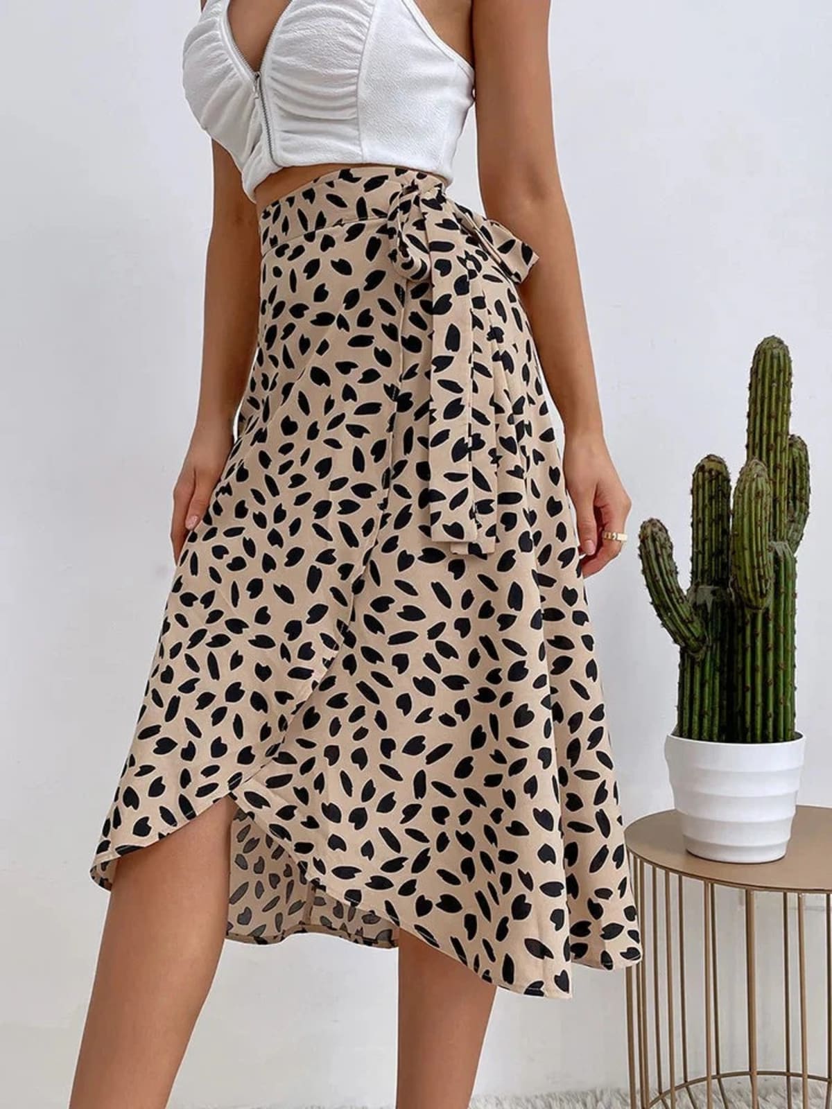 Woman in a wrap midi skirt with asymmetrical hem and tie-waist.