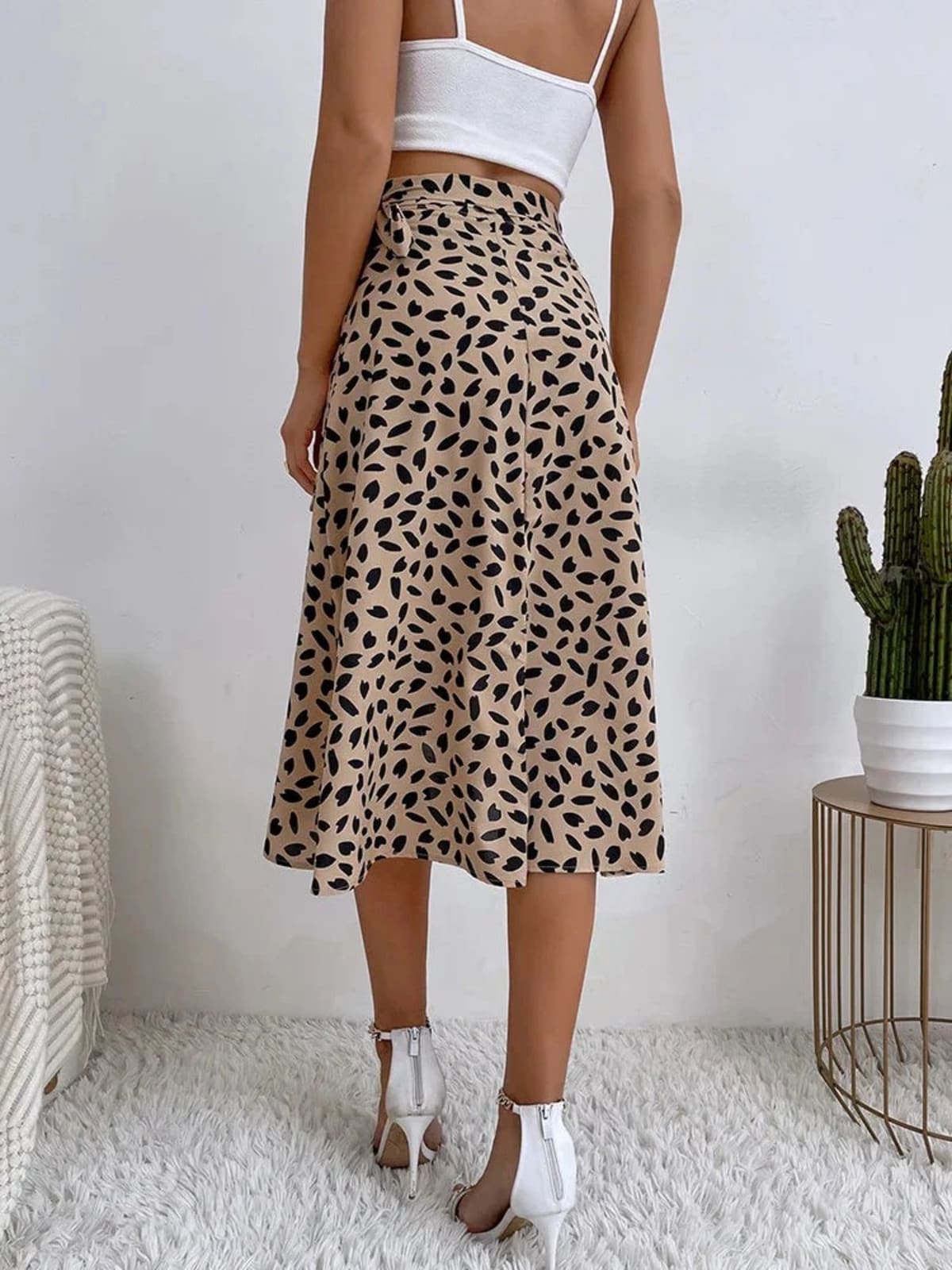 Woman in a wrap midi skirt with asymmetrical hem and tie-waist.