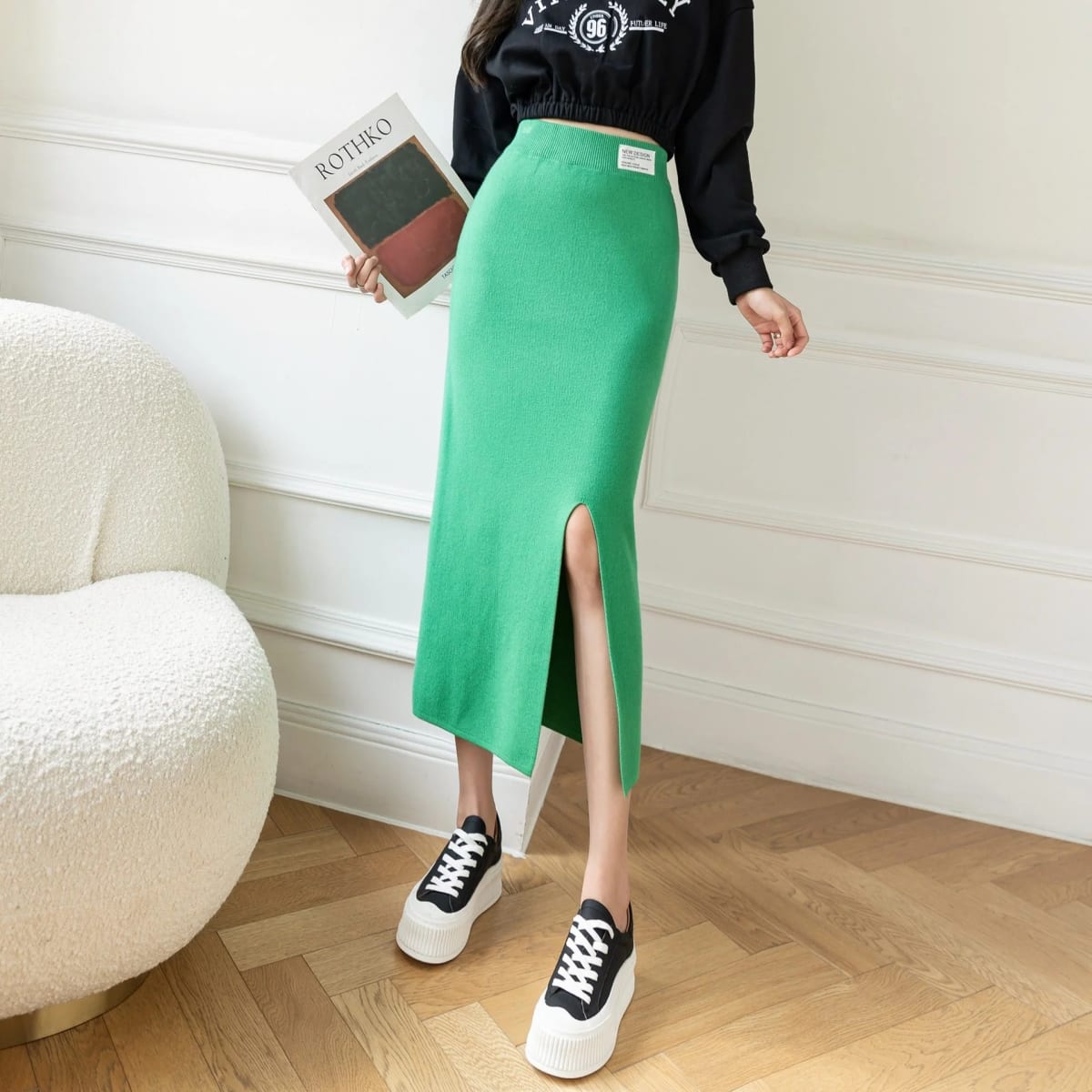 Model wearing a high-waisted knit midi pencil skirt with front slit.