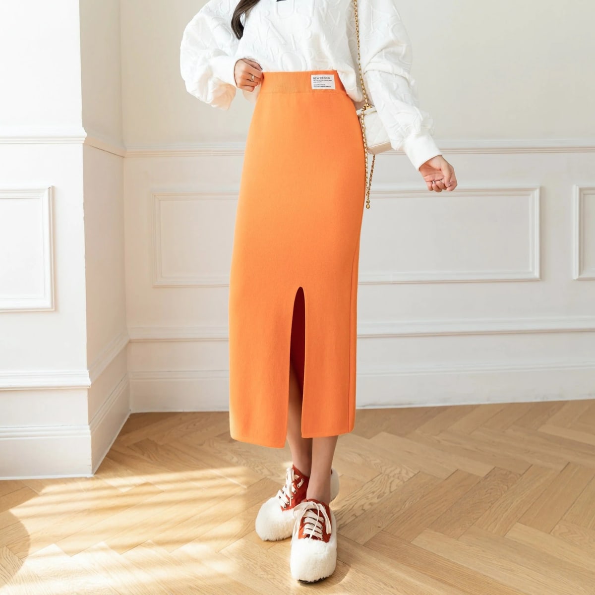 Model wearing a high-waisted knit midi pencil skirt with front slit.