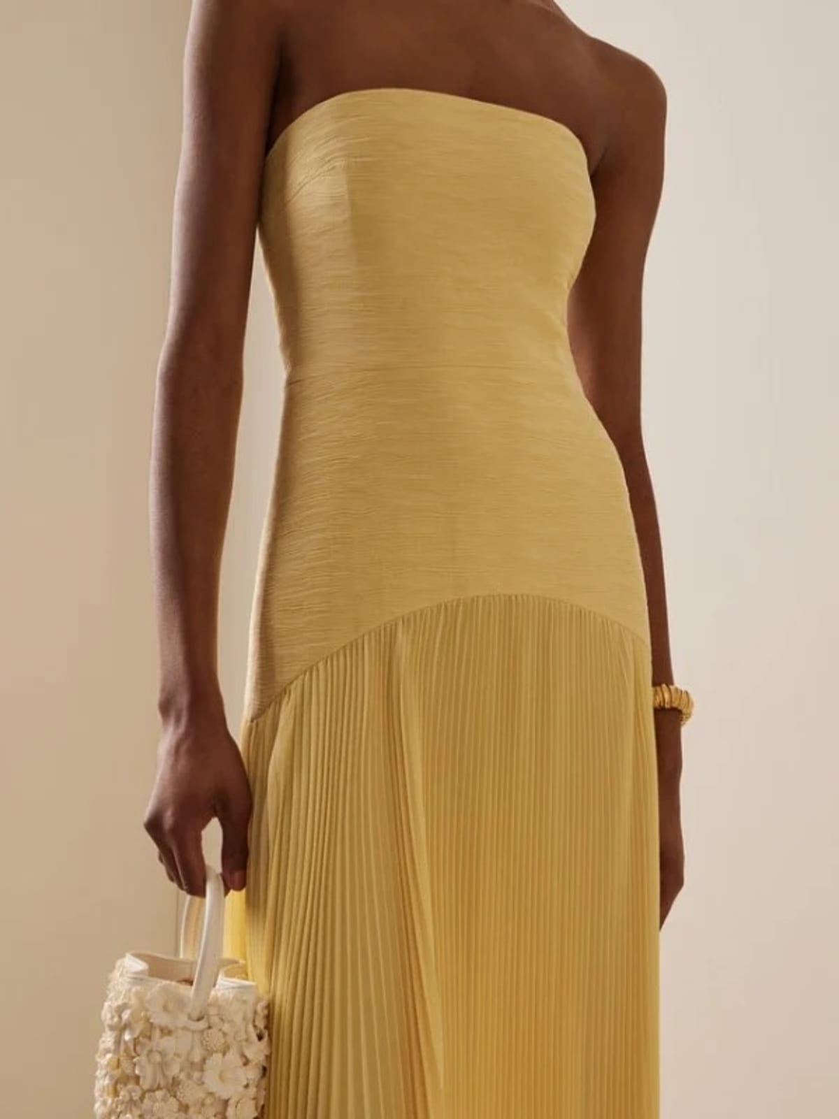 Strapless maxi dress with pleated skirt, worn at a formal event.