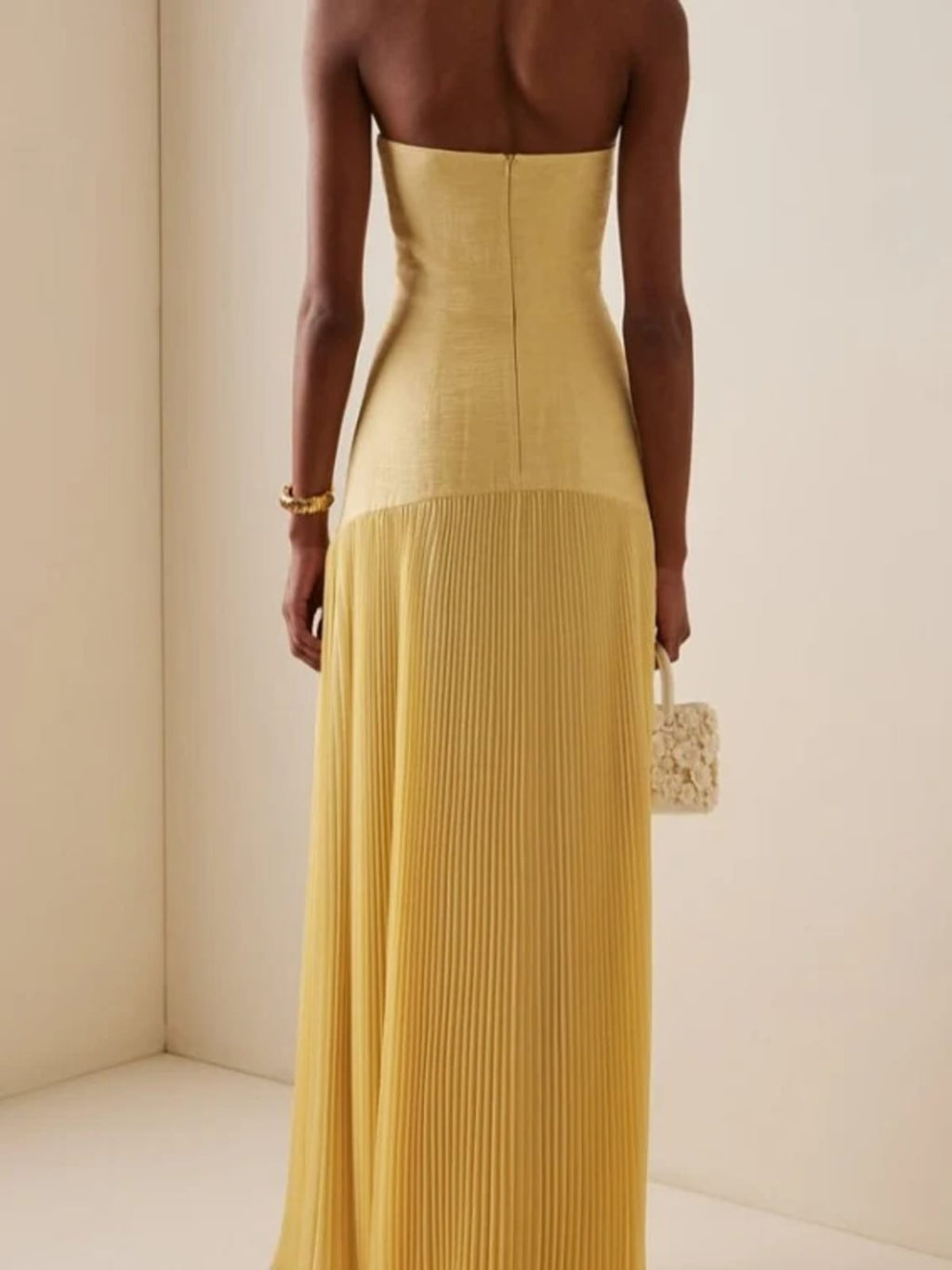 Strapless maxi dress with pleated skirt, worn at a formal event.