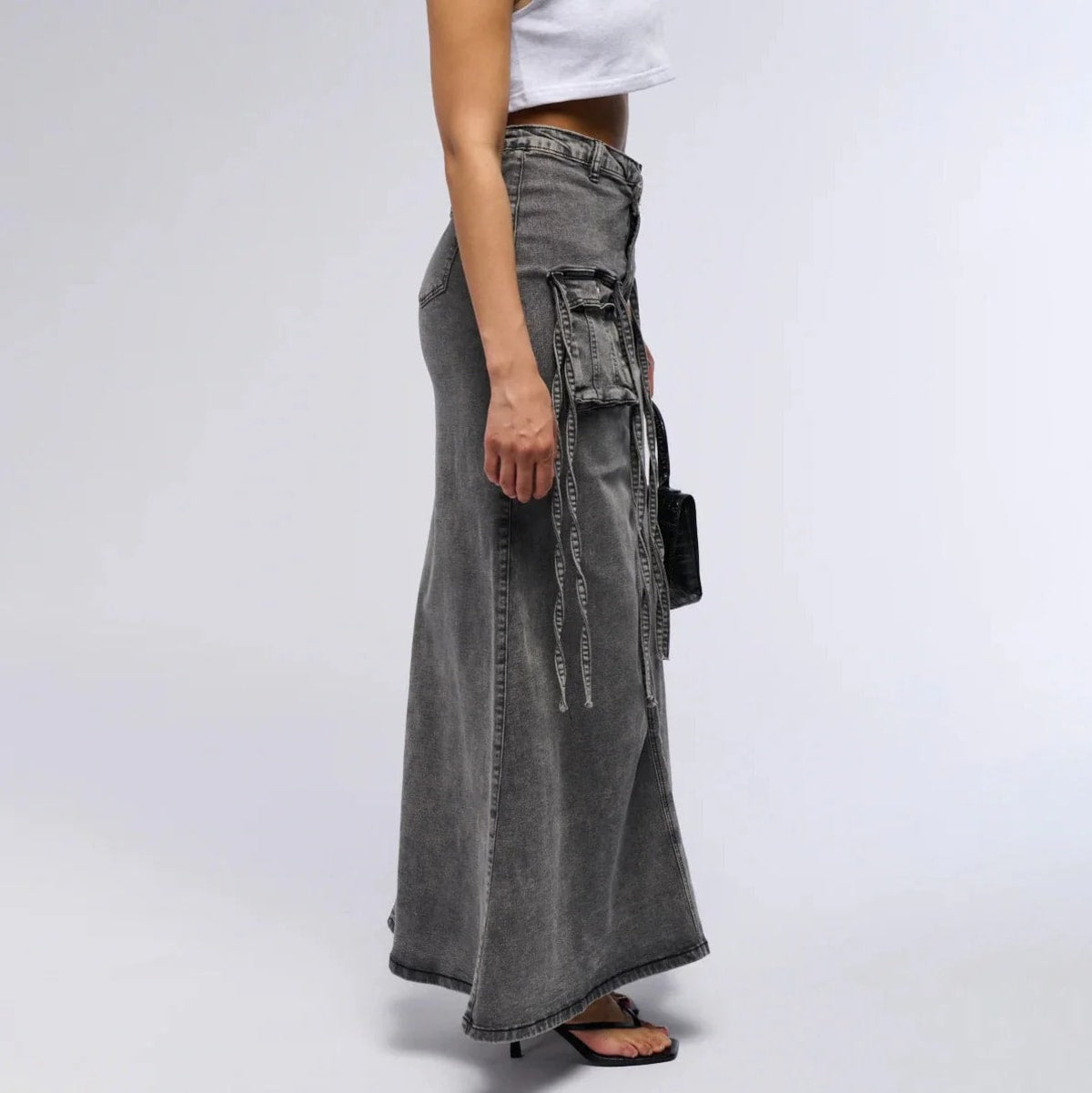 Maxi denim skirt with asymmetric waist, cargo pockets, decorative straps.