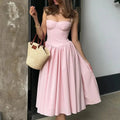 Woman wearing a bustier A-line midi dress with spaghetti straps.