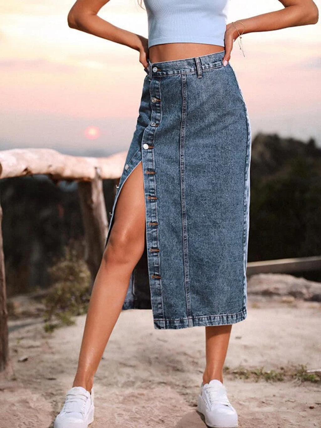 Woman wearing a high-waisted denim midi skirt with a button-front and side slit outdoors.